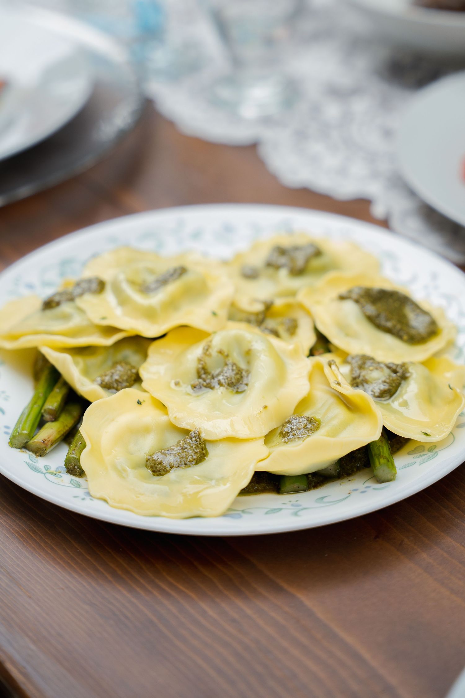Plate of homemade ravioli pasta with asparagus served on white china.