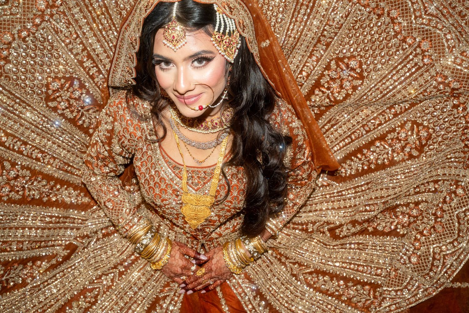 Close-up shots of intricate gold embroidery details on an orange bridal lehenga.
