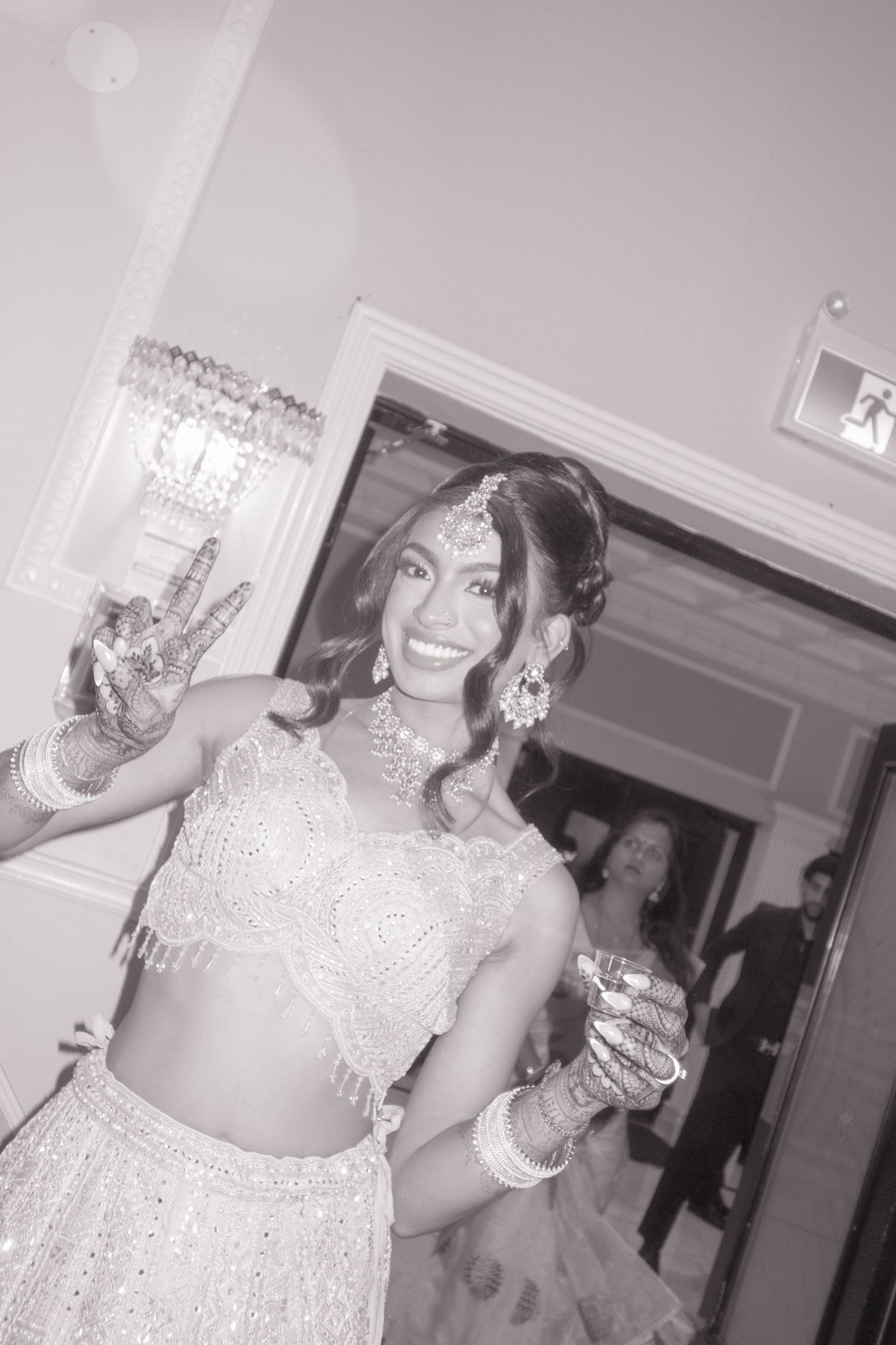 Person in traditional South Asian attire making peace sign at formal celebration.