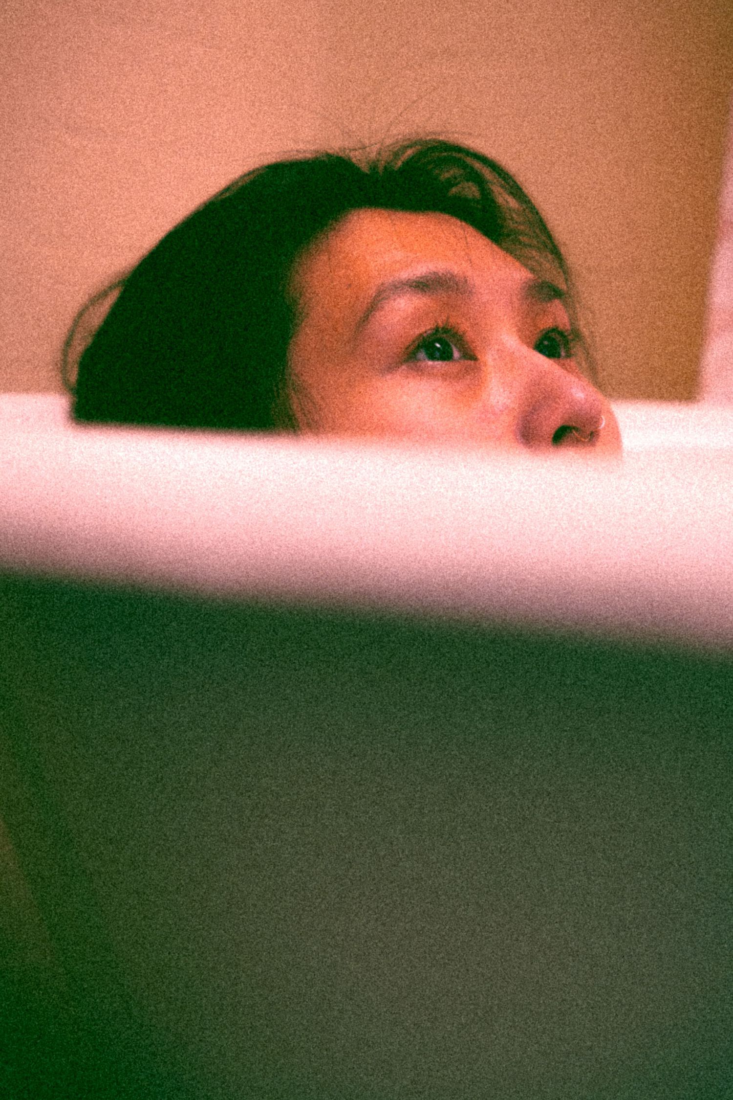Artistic close-up shot with warm tones showing partial face above frame edge.