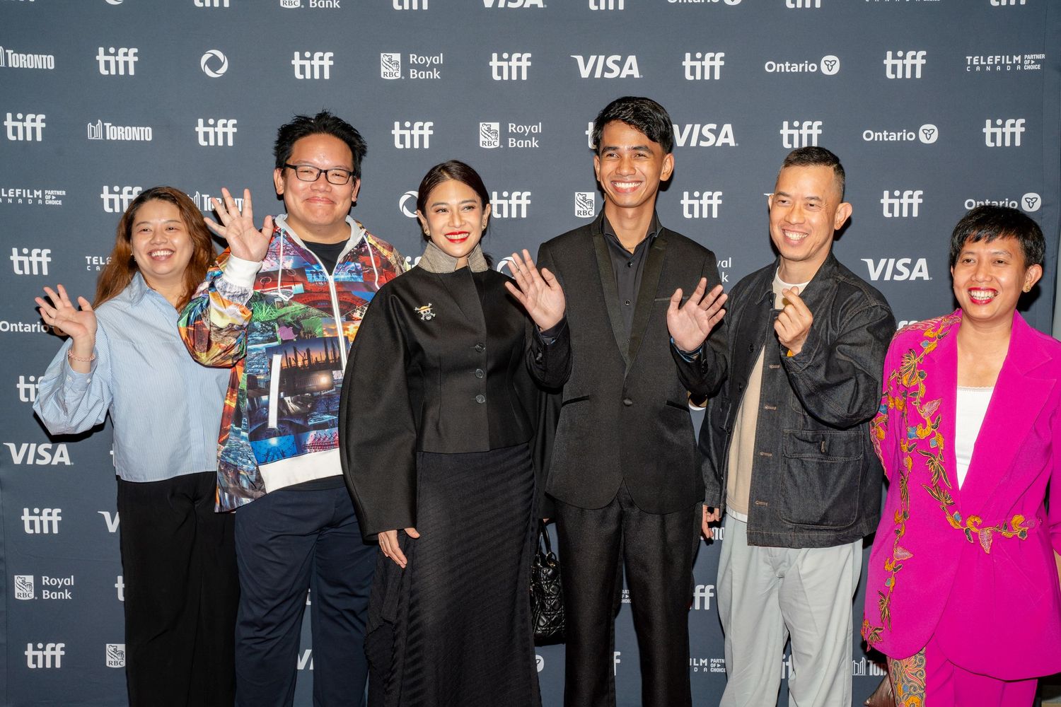 Film festival attendees standing together against TIFF step and repeat banner backdrop.