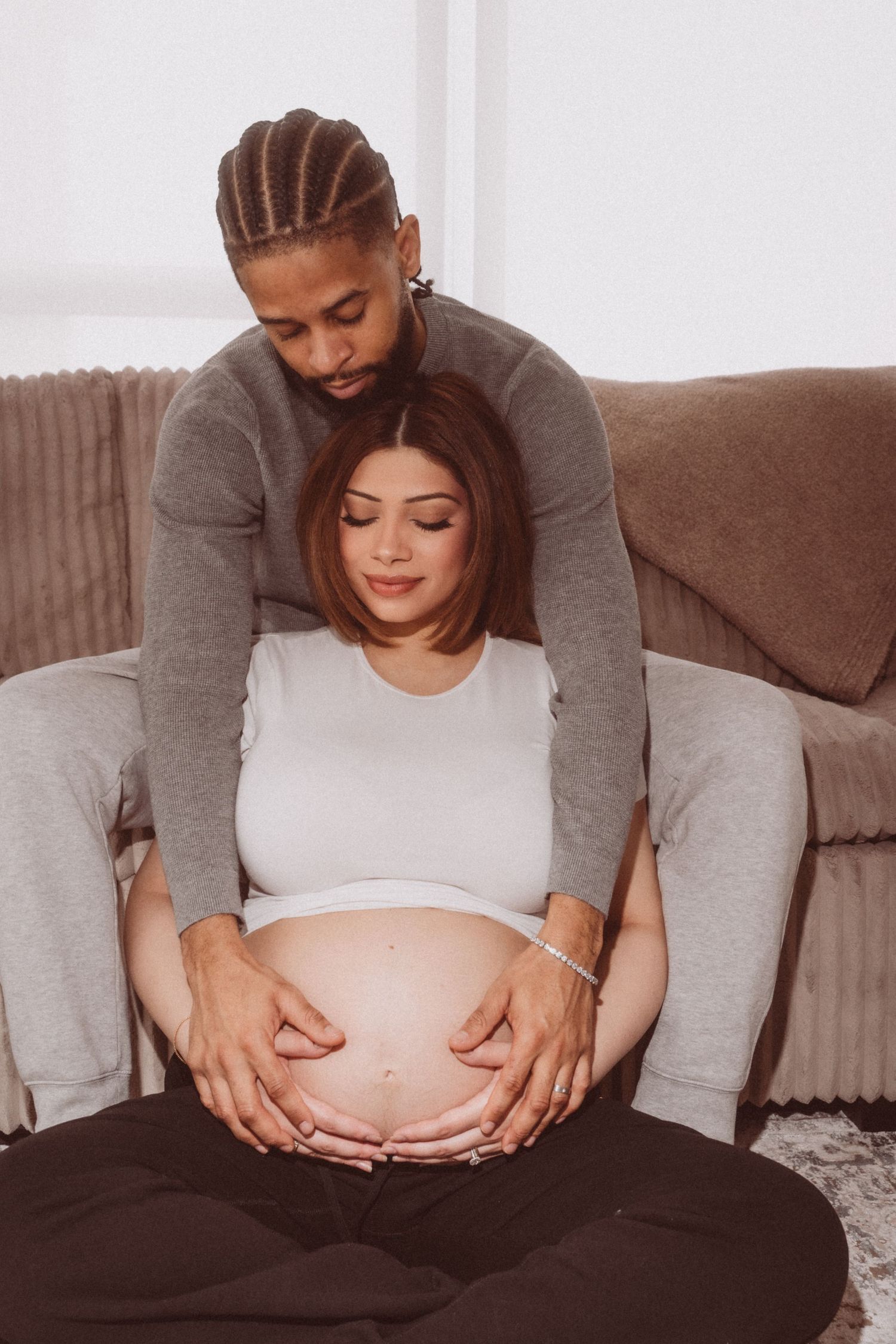 A series of pregnancy progression photos showing a growing baby bump being cradled with gentle hands in a cozy home setting.