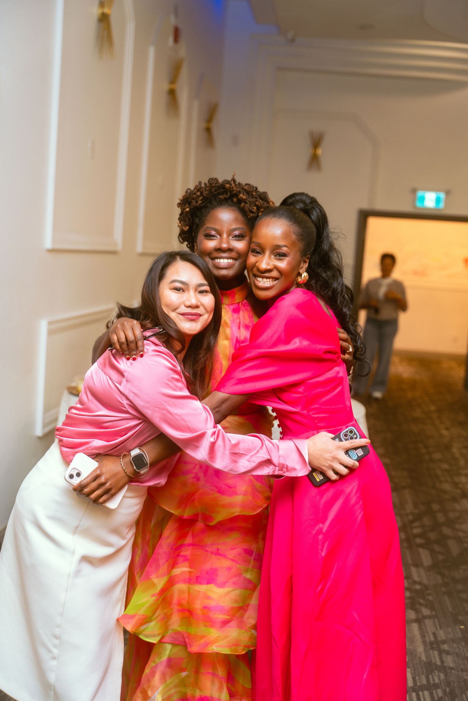 Attendees share warm embraces and smiles at an indoor celebration event.