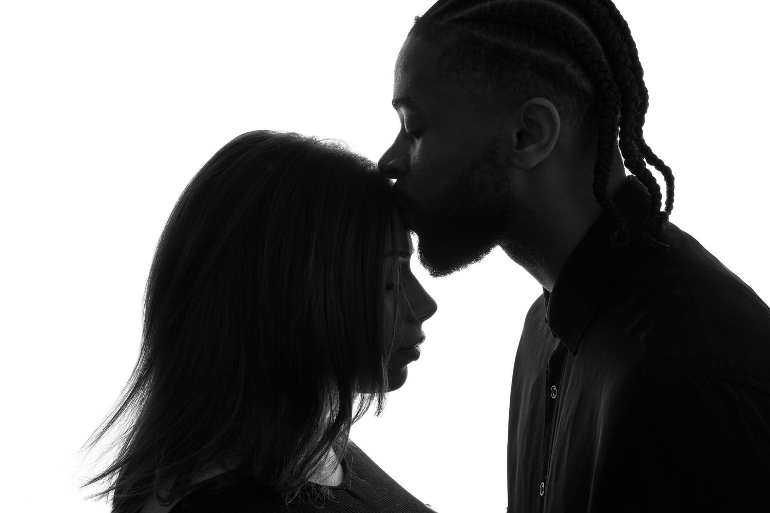 A row of black and white silhouettes of people in profile against a white background.