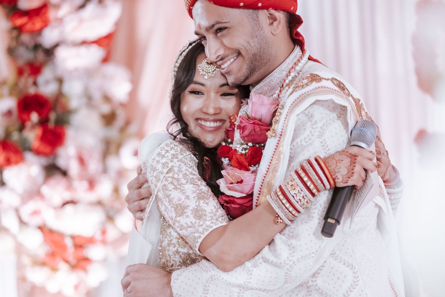 Indian bride and groom sharing a warm hug and smiling during their traditional Hindu wedding celebration.