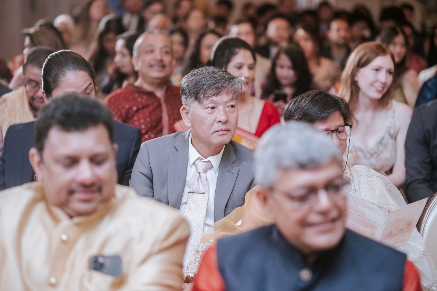 Guests dressed in traditional and formal attire seated at an Indian wedding ceremony.