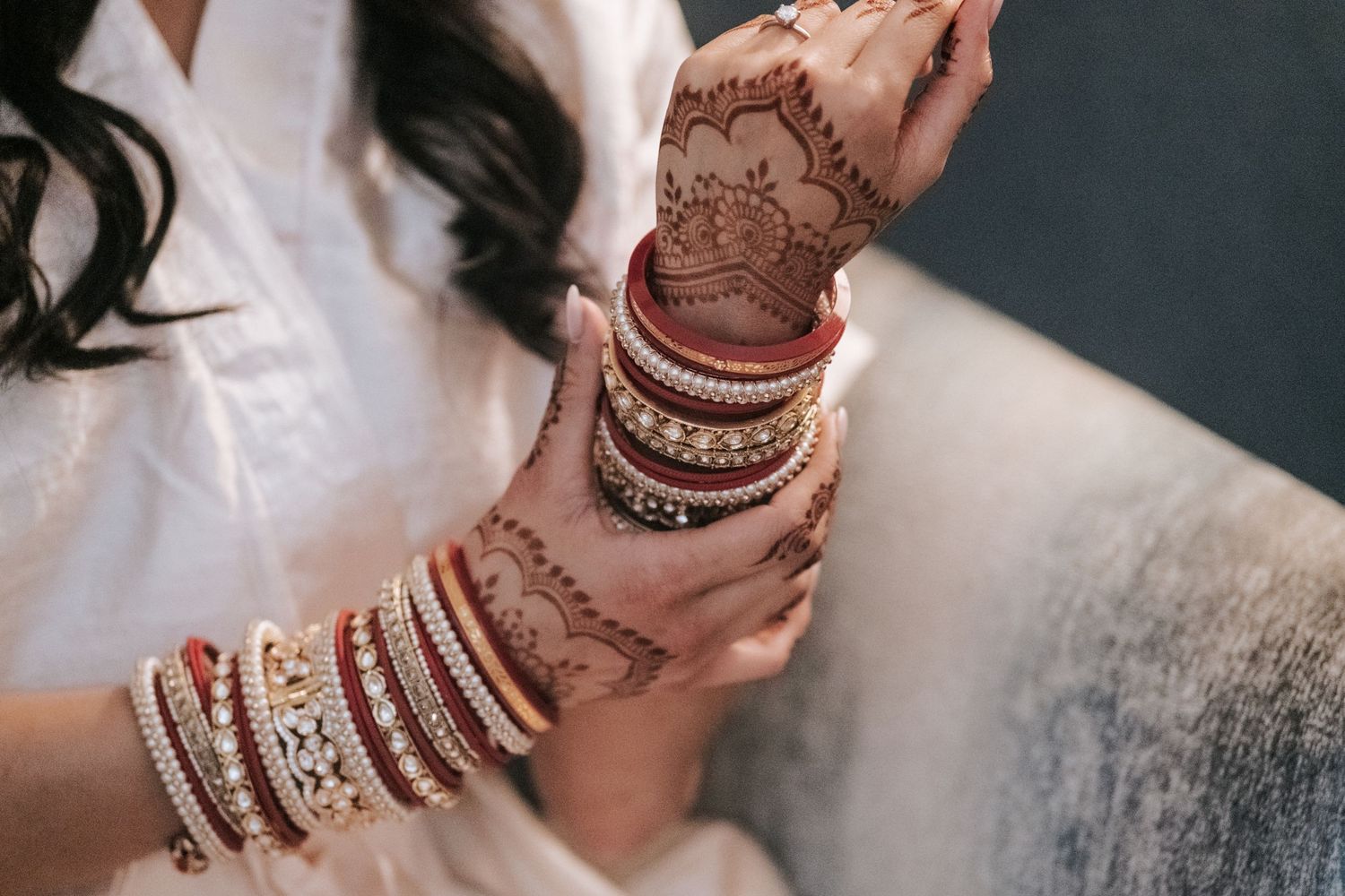 Indian bride wearing intricate mehndi henna with red and gold traditional wedding bangles.