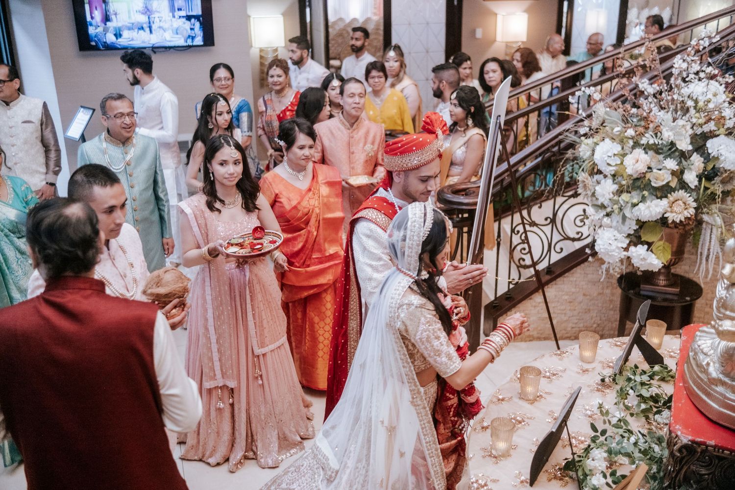 Indian wedding guests gather around couple during traditional Hindu ceremony rituals at elegant venue.