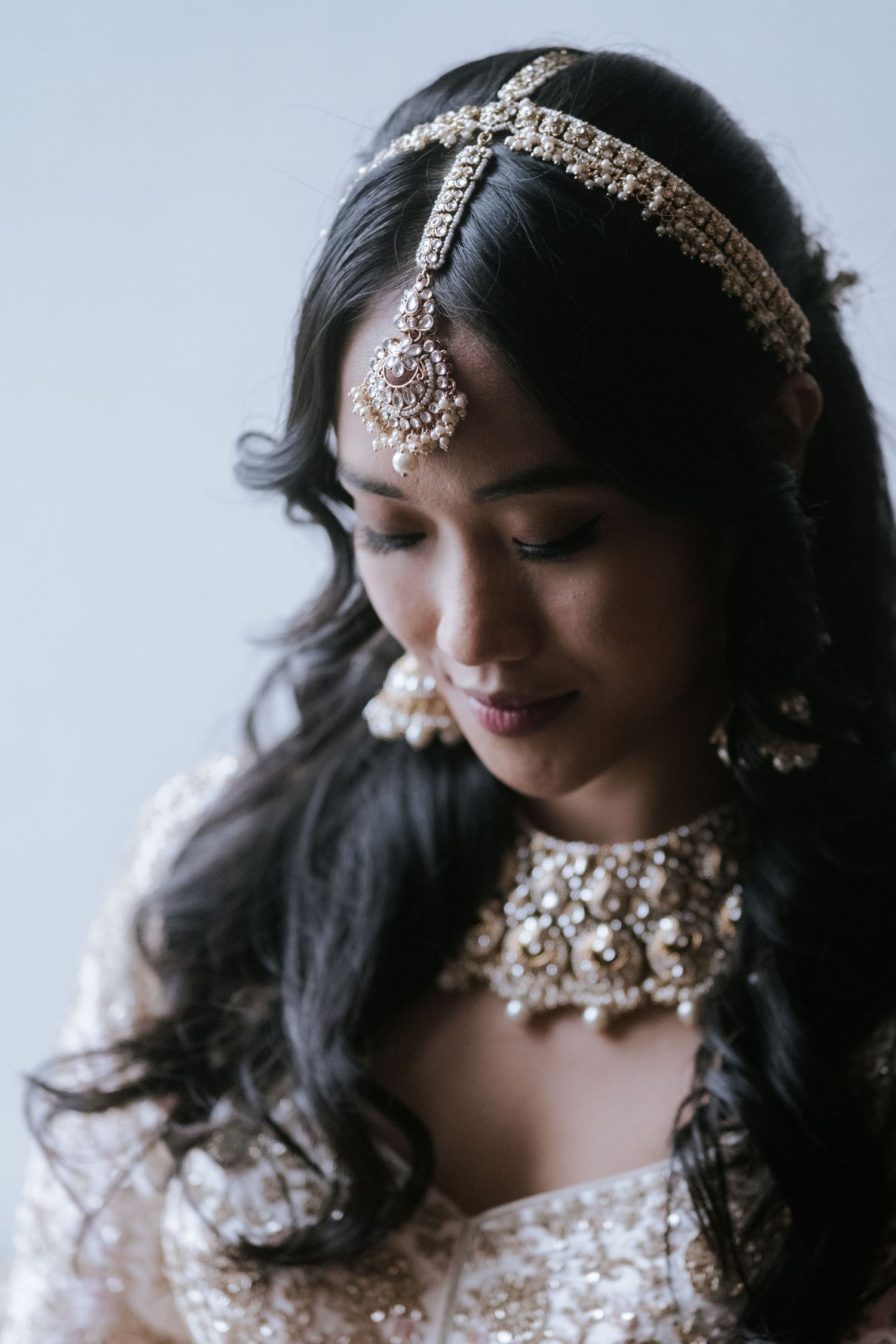 Indian bride wearing maang tikka headpiece with kundan necklace and traditional bridal jewelry.