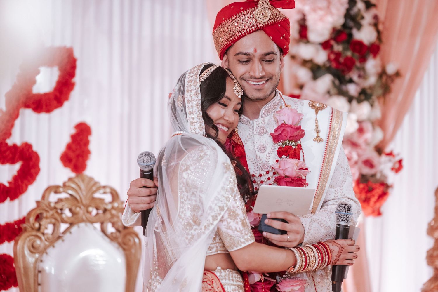 Indian bride and groom sharing a tender embrace while reading vows during traditional Hindu wedding ceremony.