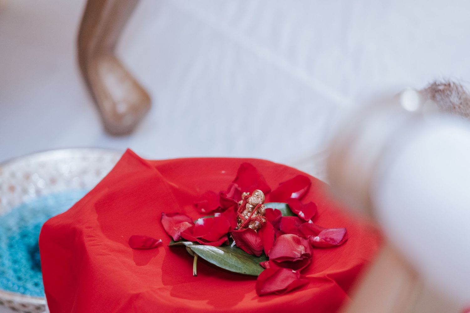 Red rose boutonniere with petals on red fabric for an Indian wedding ceremony decoration.