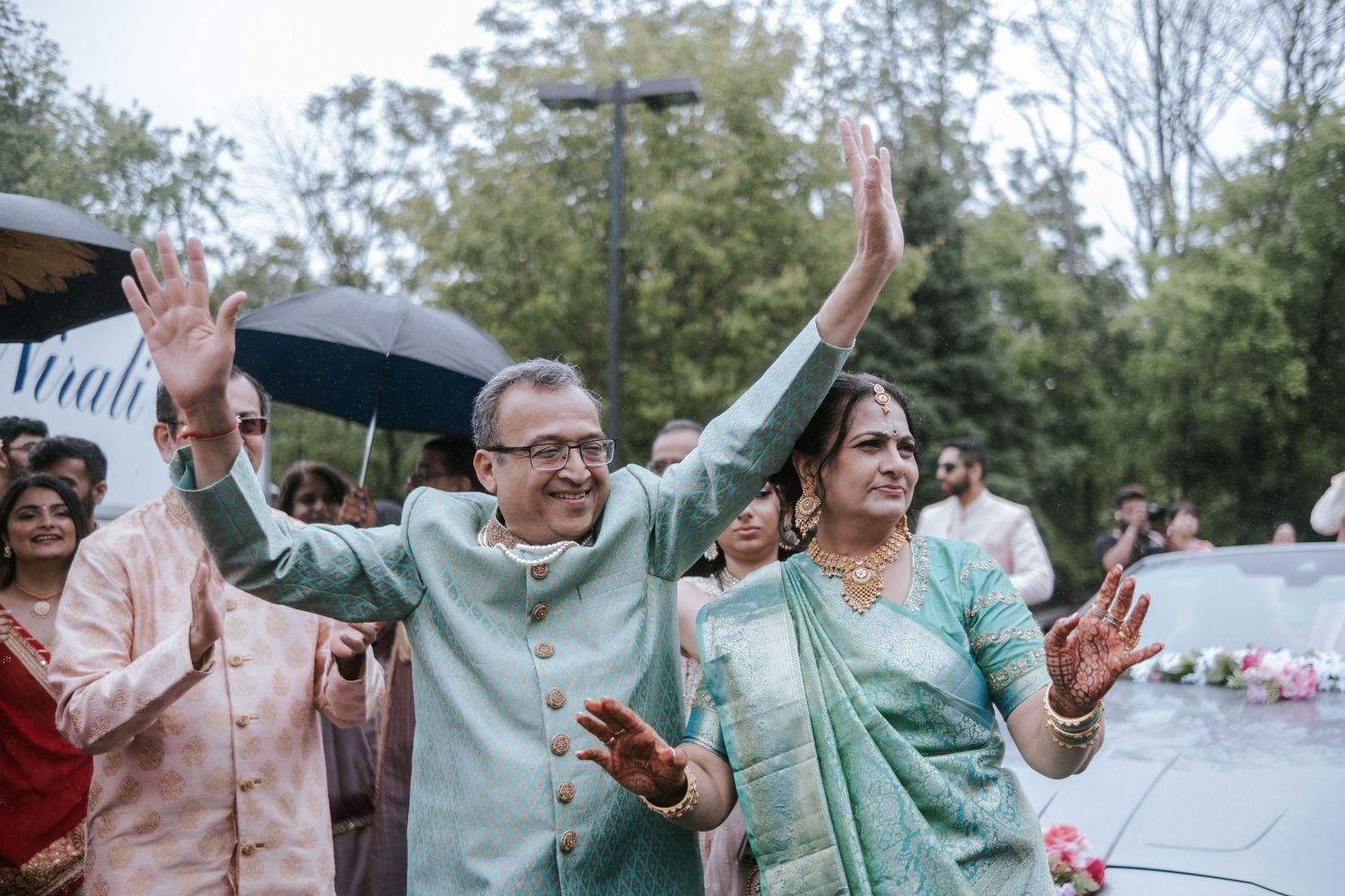 Couple in traditional Indian attire dancing joyfully outdoors at a festive wedding celebration.
