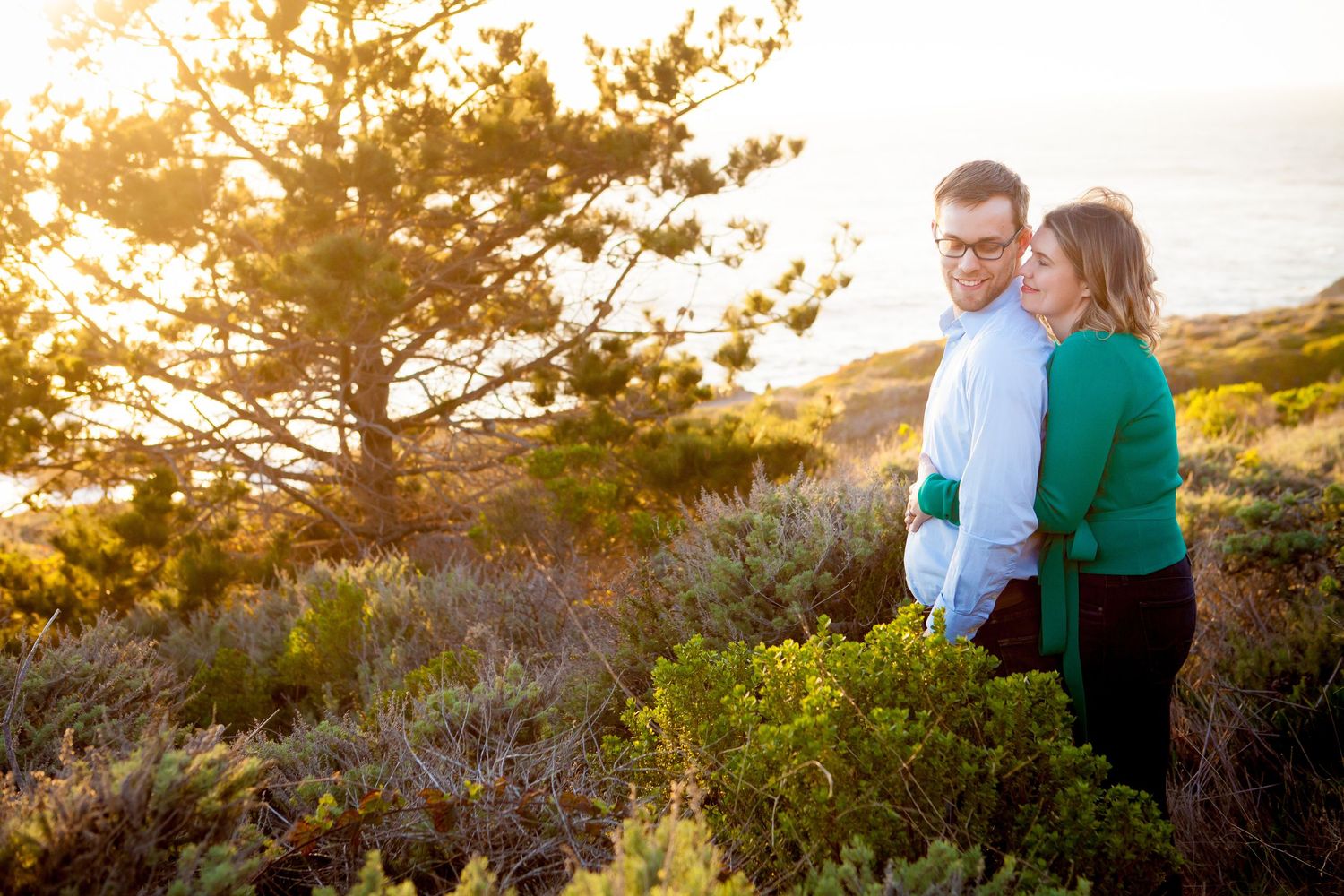 Couple walking together during golden hour in a coastal landscape with wildflowers.