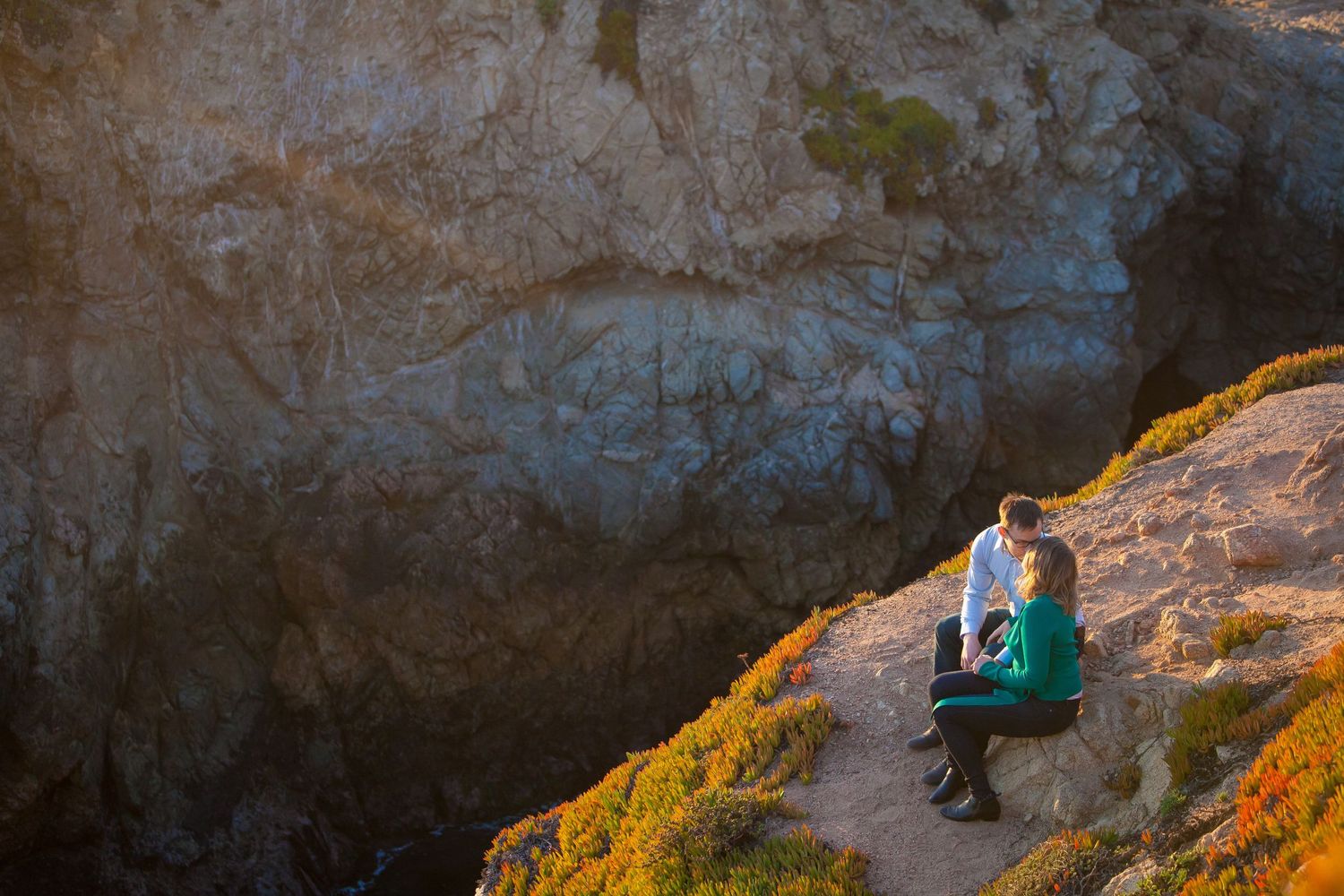 A scenic coastal cliff trail with yellow wildflowers along the rocky edge.