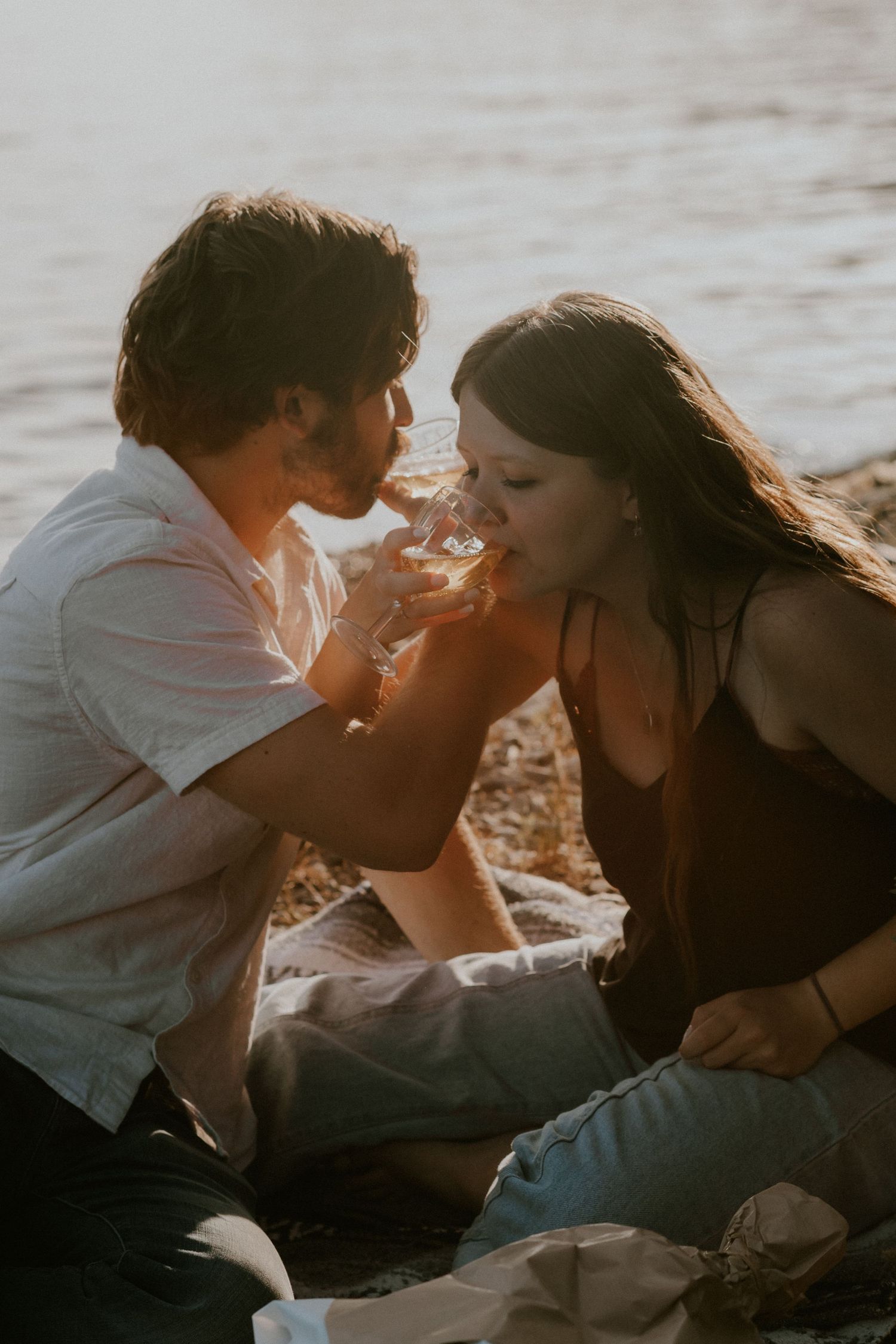A couple shares an intimate moment while smoking together at sunset on a beach.