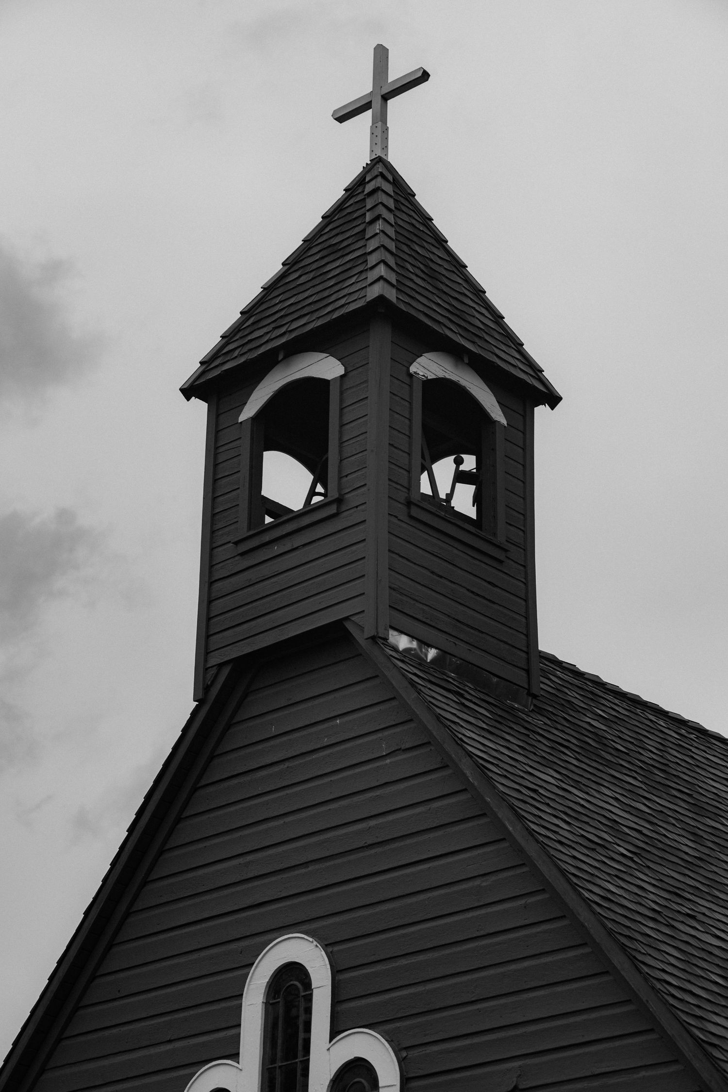 Black and white photo series of a church steeple with cross showing different angles against cloudy sky.