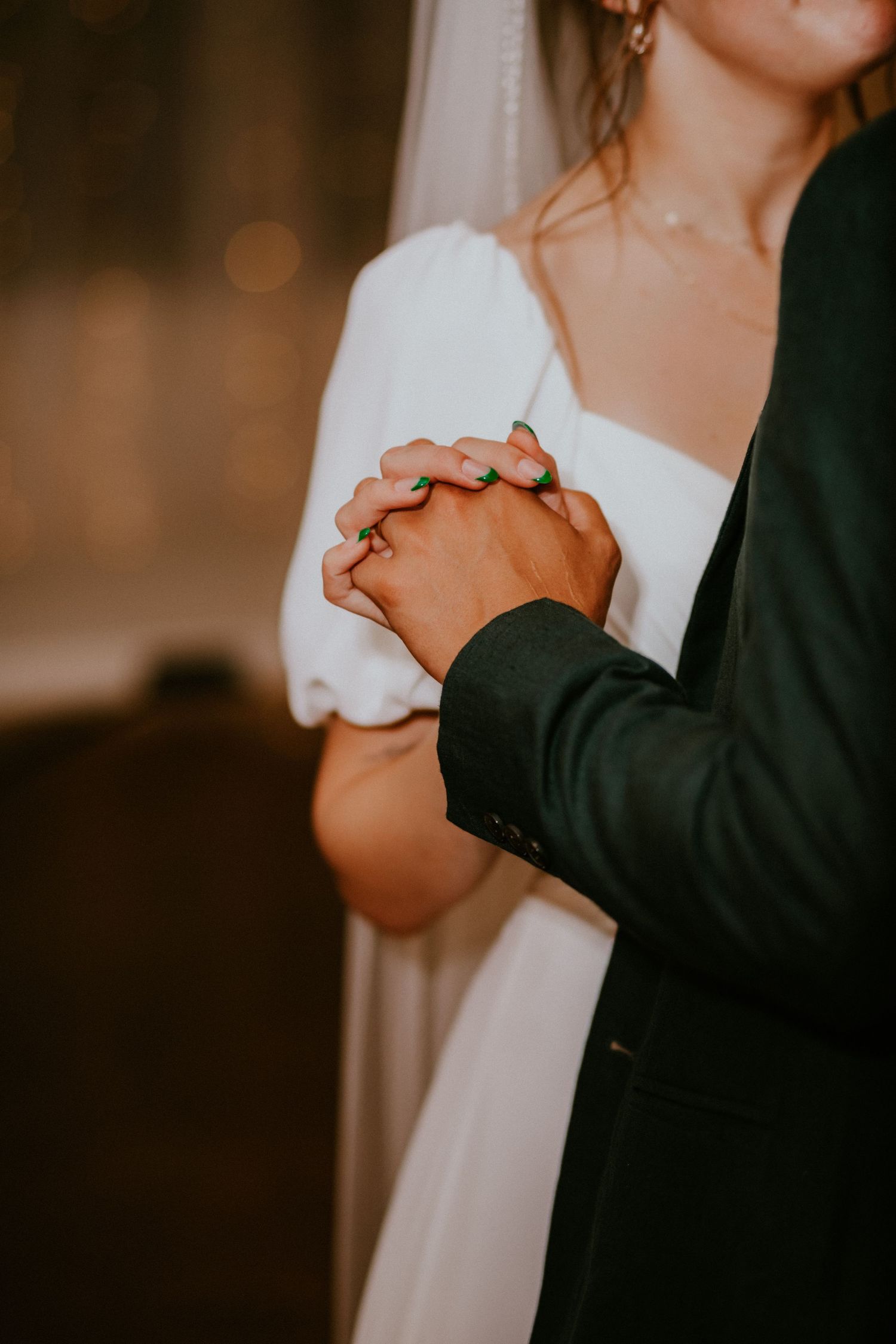 A tender black and white photograph captures newlyweds holding hands during their wedding ceremony.