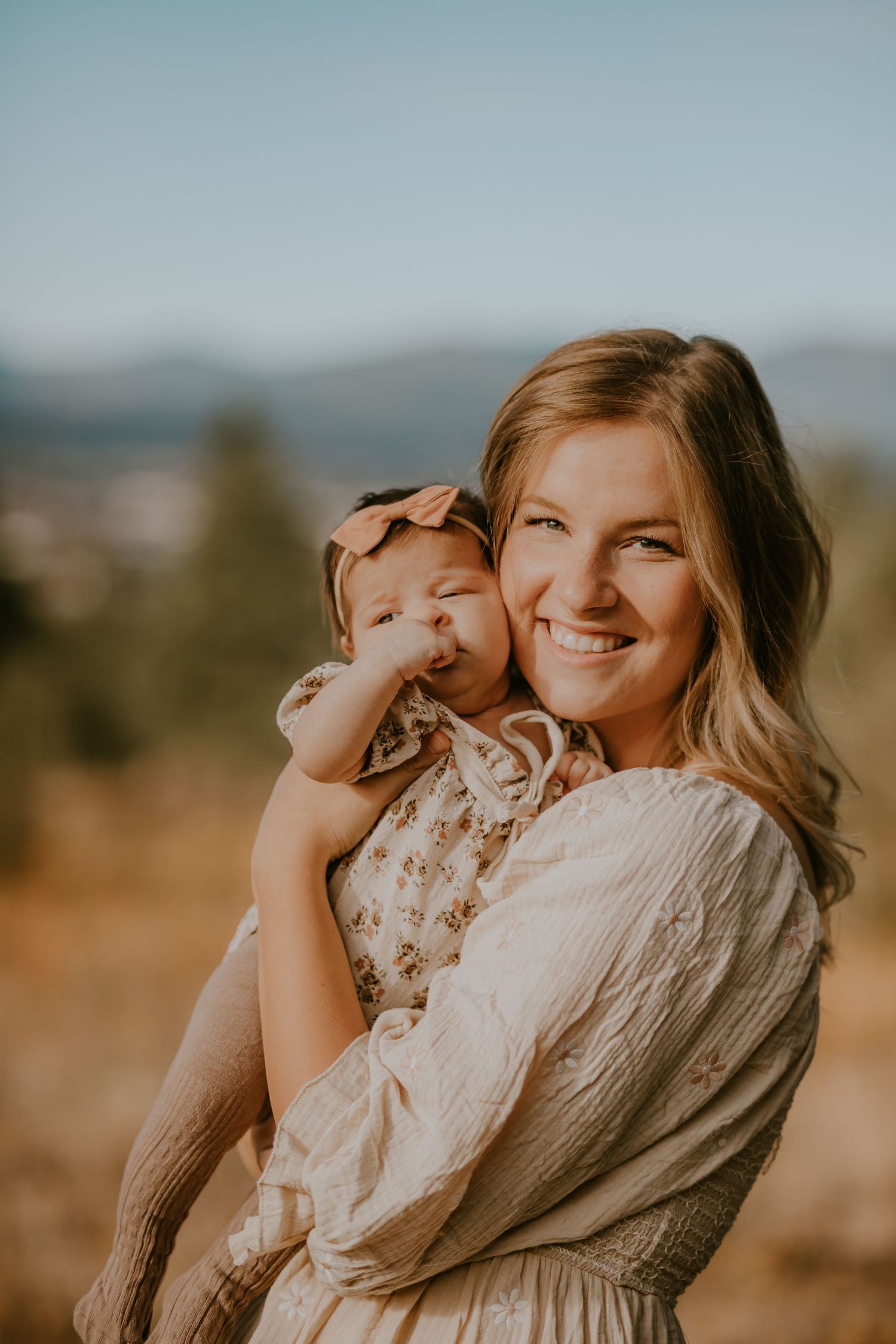 A warm sunset photoshoot captures tender moments between a parent and child in an outdoor desert setting.