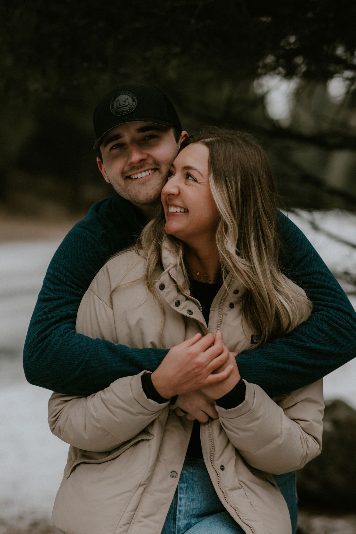 A romantic winter photoshoot featuring a couple embracing outdoors in warm winter clothing.
