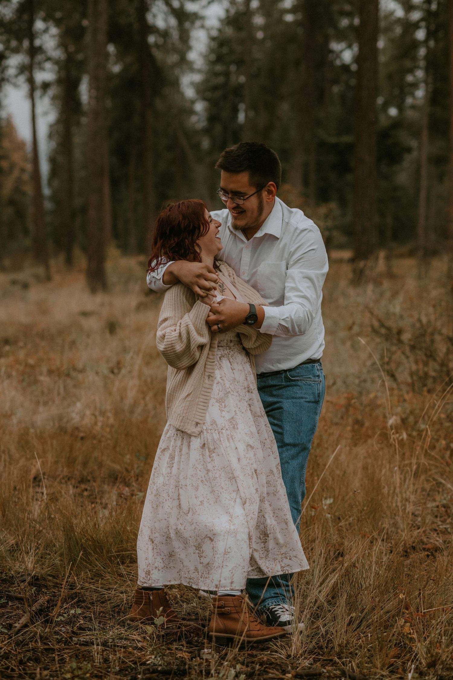 Parent and toddler share tender moments in a rustic forest setting with golden grass and tall trees.