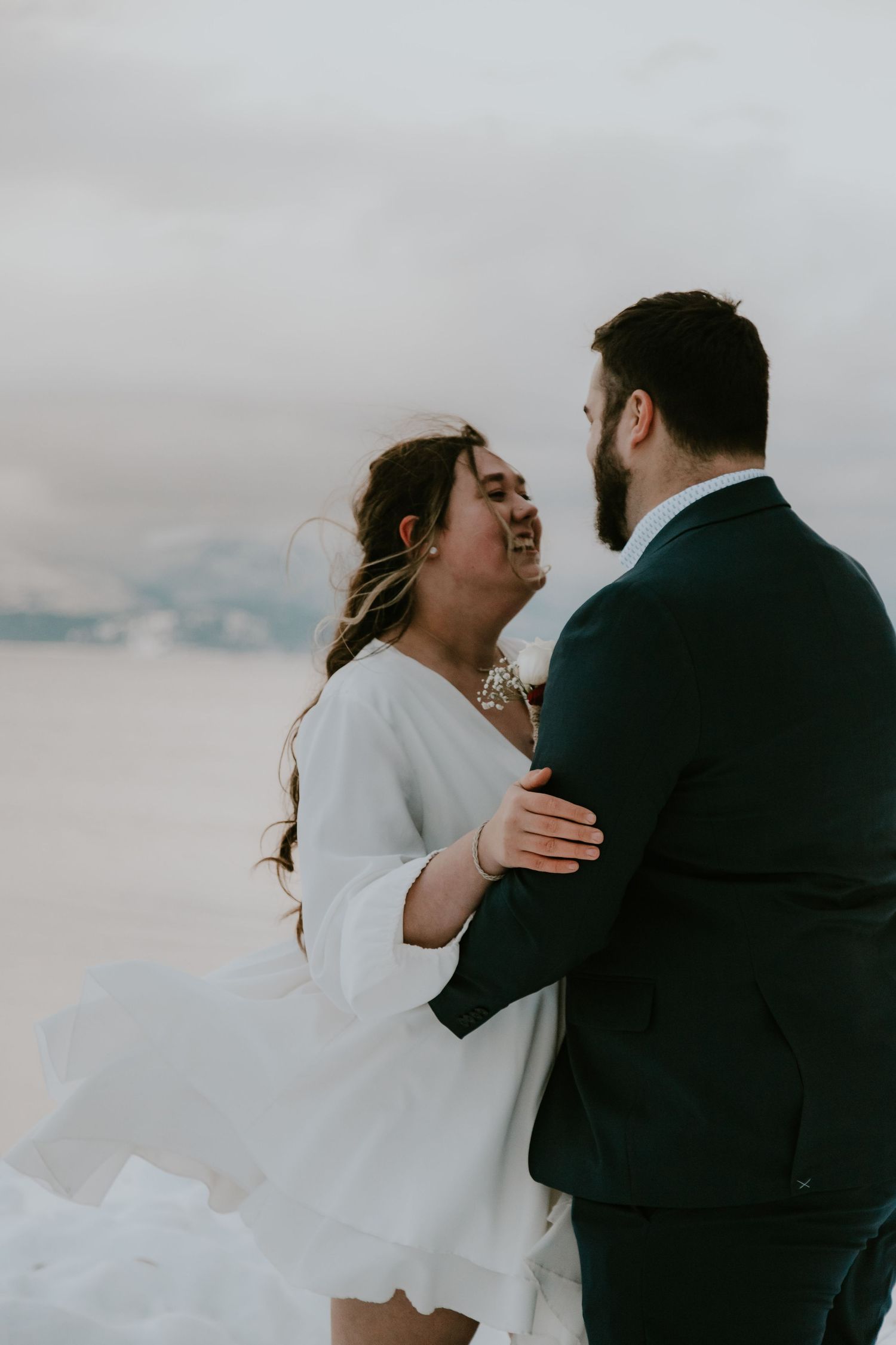A series of romantic wedding photos showing tender moments between a couple embracing against a cloudy sky backdrop.