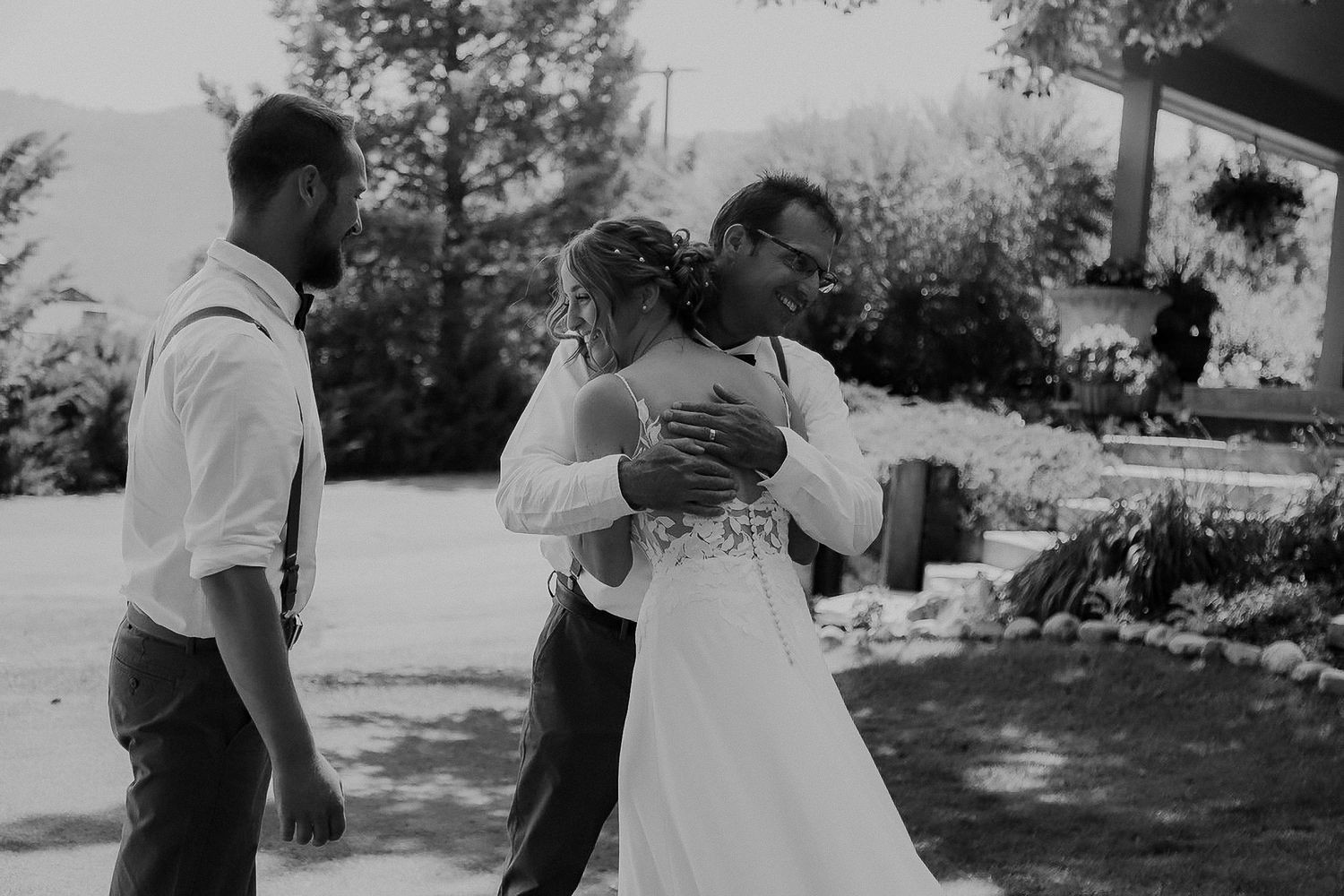 A black and white photo shows people dancing and embracing outdoors during a special celebration.