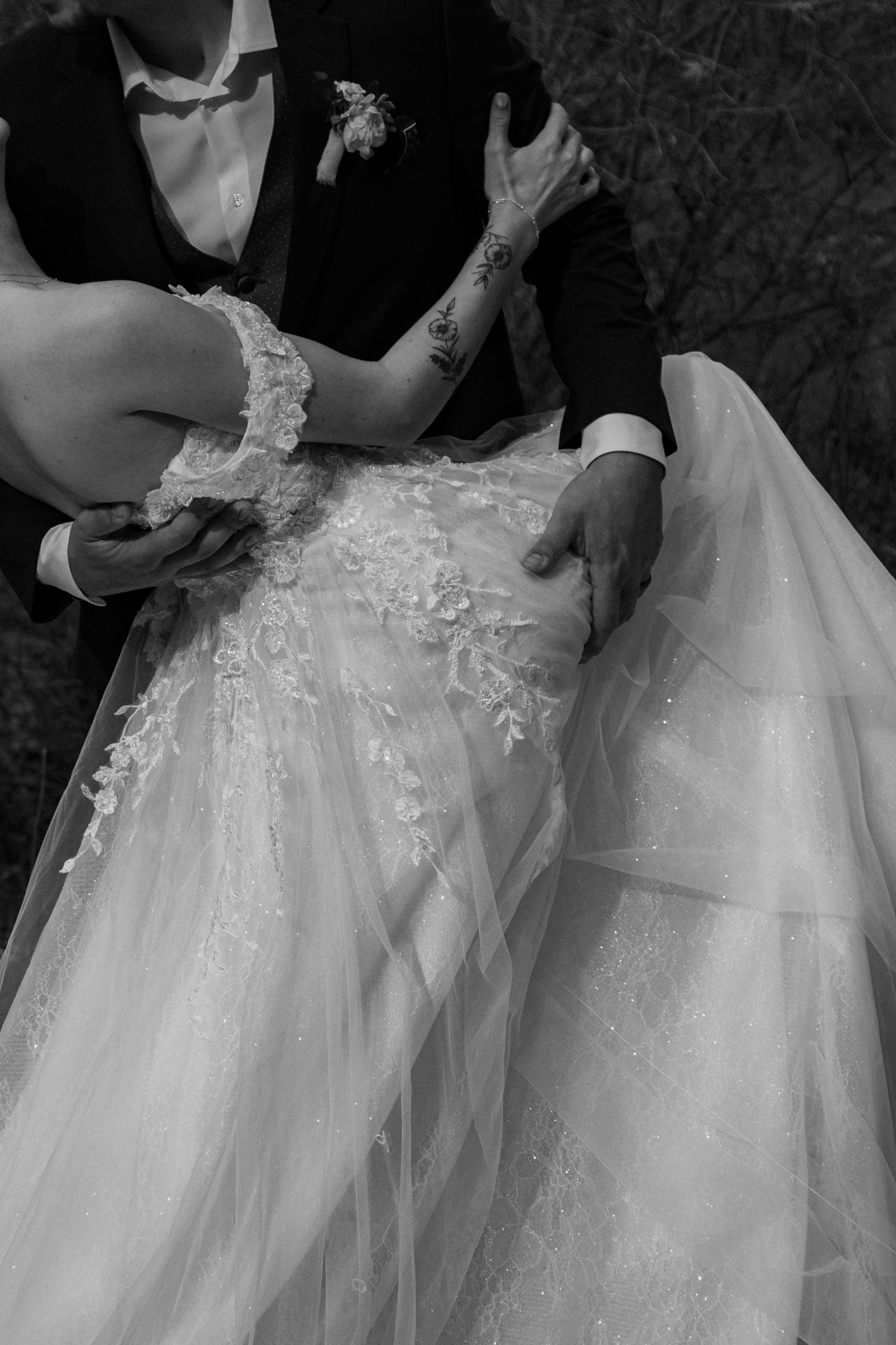 A close-up detail shot of a white wedding dress with delicate lace and tulle fabric details.