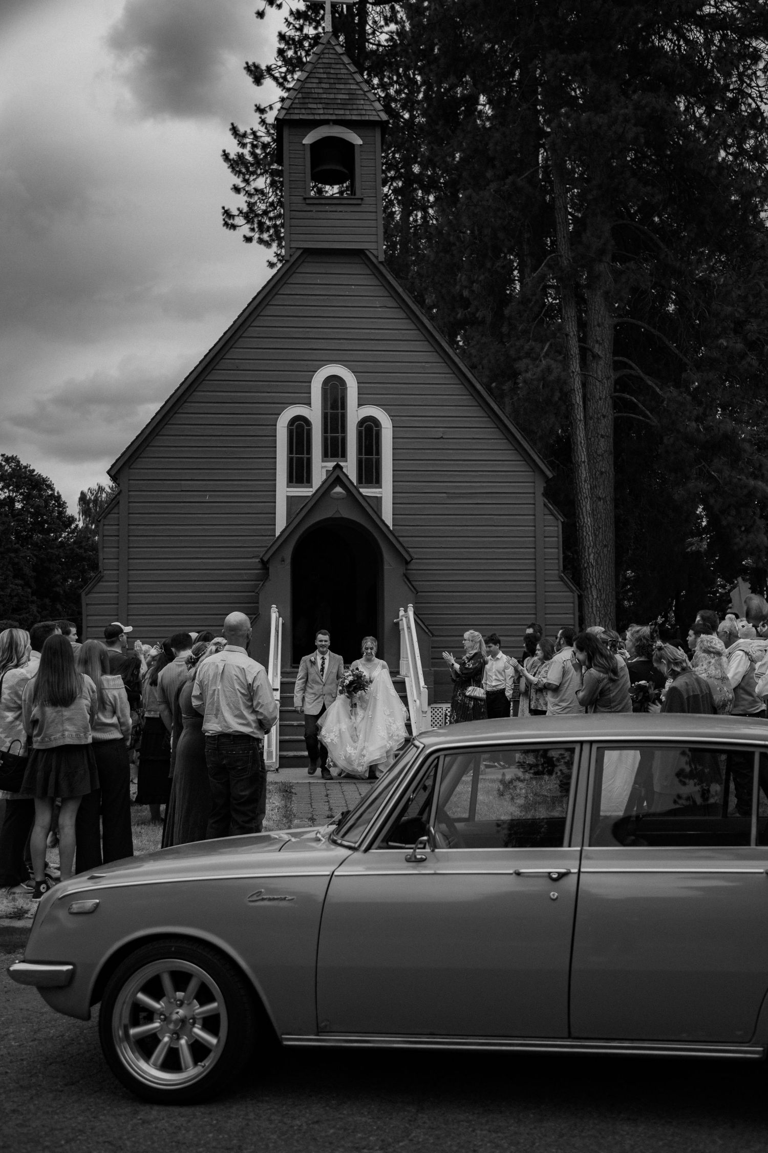 A collage sequence showing a vintage silver sportscar parked outside a small white chapel during a gathering of people.