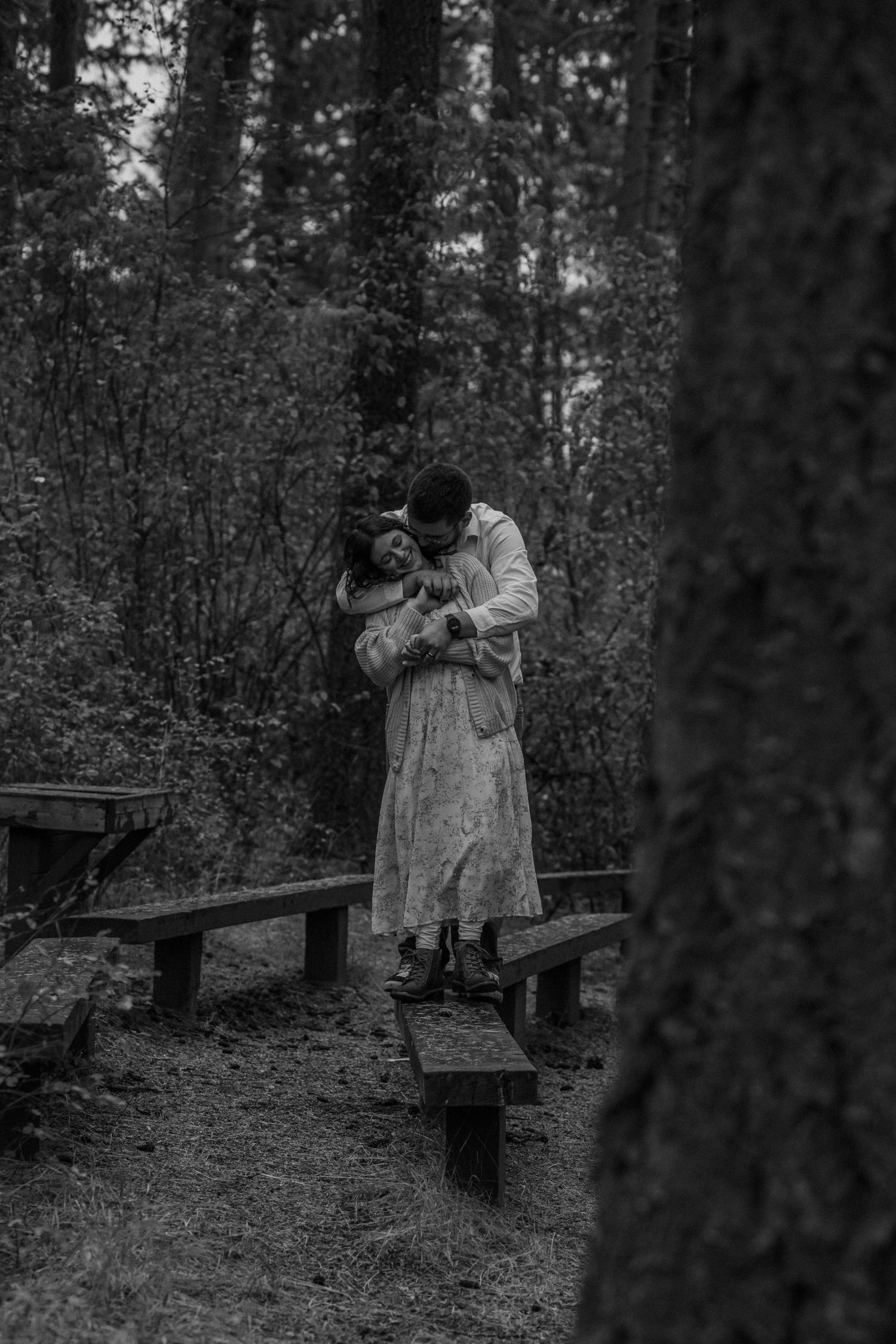 A series of black and white photographs showing people in Victorian-era dress walking across a wooden footbridge in a forest.