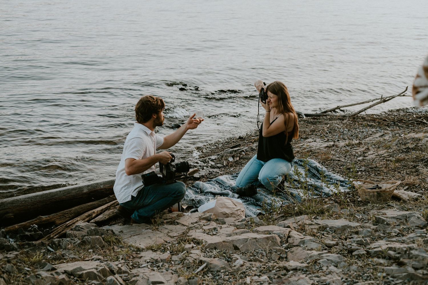 A couple sharing an intimate moment on a rocky beach at sunset.