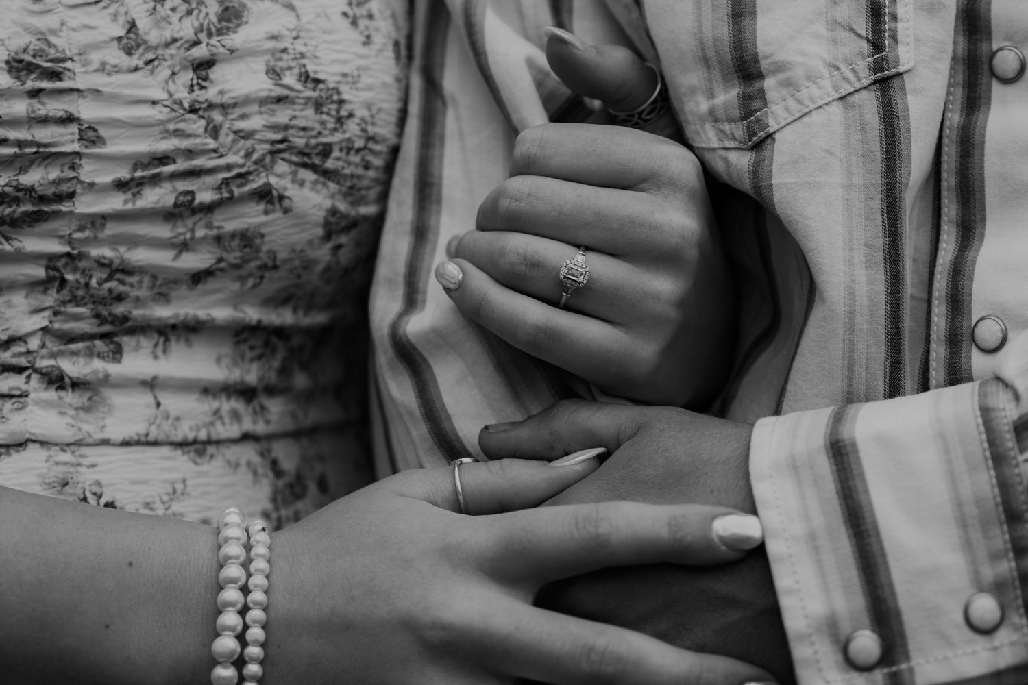 Black and white vintage photograph showing a close-up of hands gently holding delicate pearl jewelry.