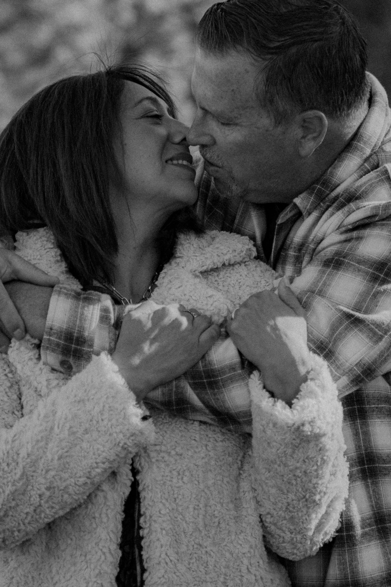 A romantic black and white photo sequence showing a couple in a plaid shirt and white sweater sharing tender moments together.