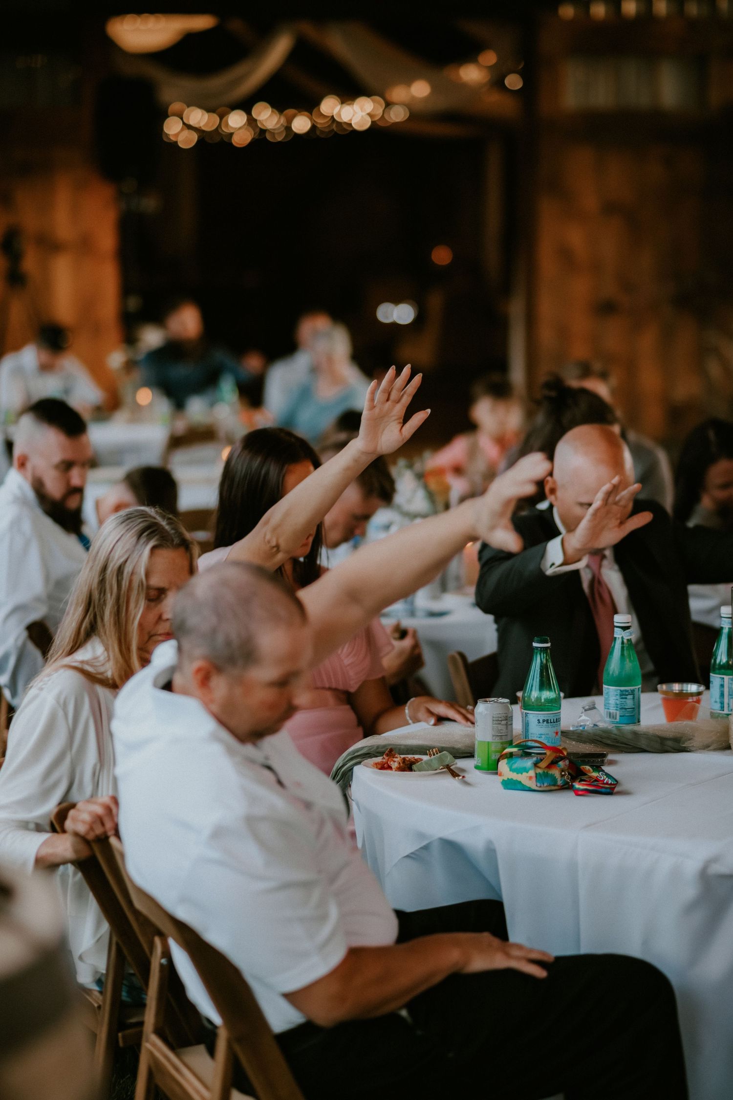 Five side-by-side shots showing guests at a wedding reception enjoying dinner and raising their arms in celebration.