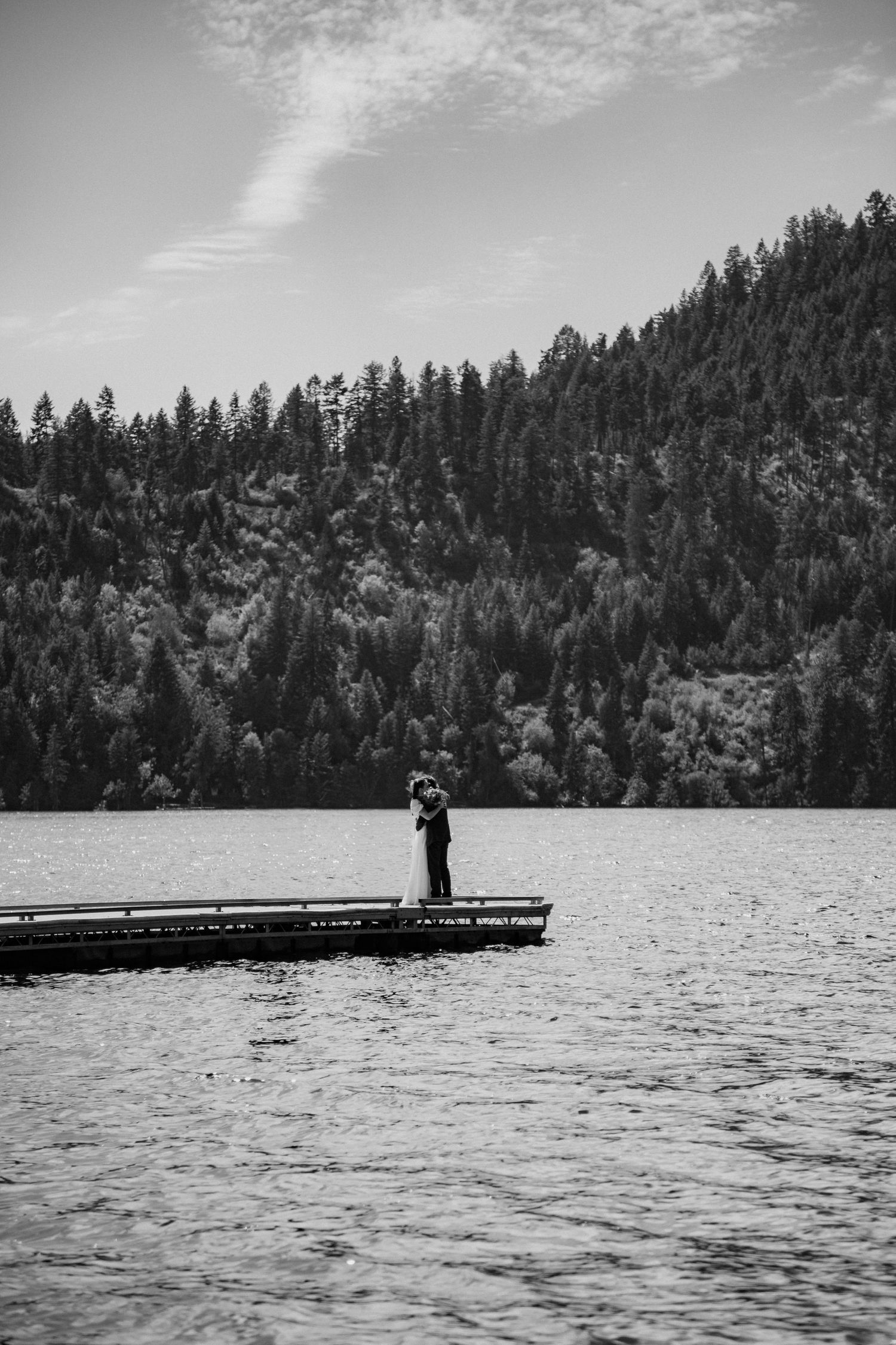 Black and white photo sequence showing silhouettes at the end of a wooden dock on a peaceful mountain lake.