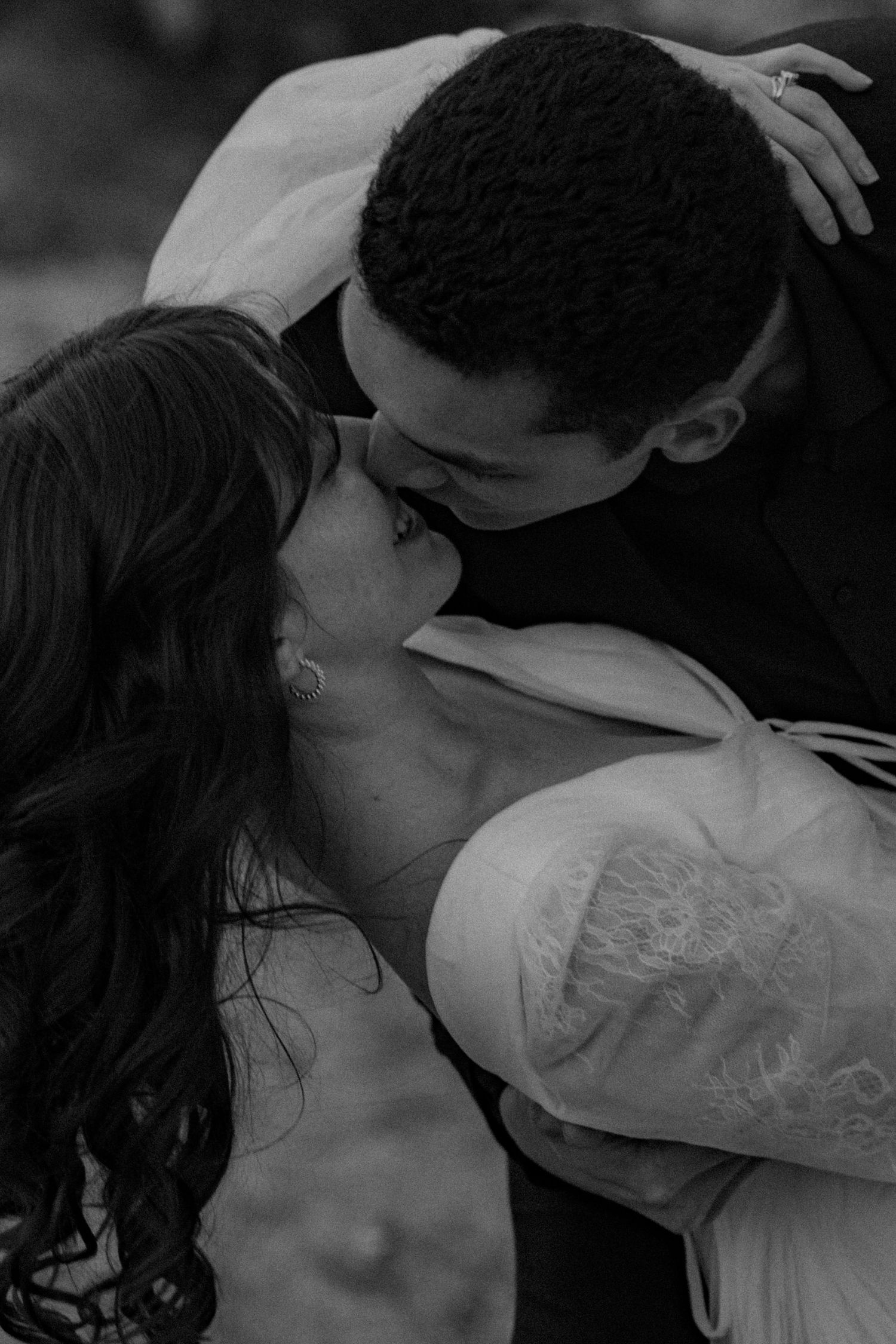 A tender black and white portrait of a romantic couple sharing an intimate kiss in an artistic close-up shot.