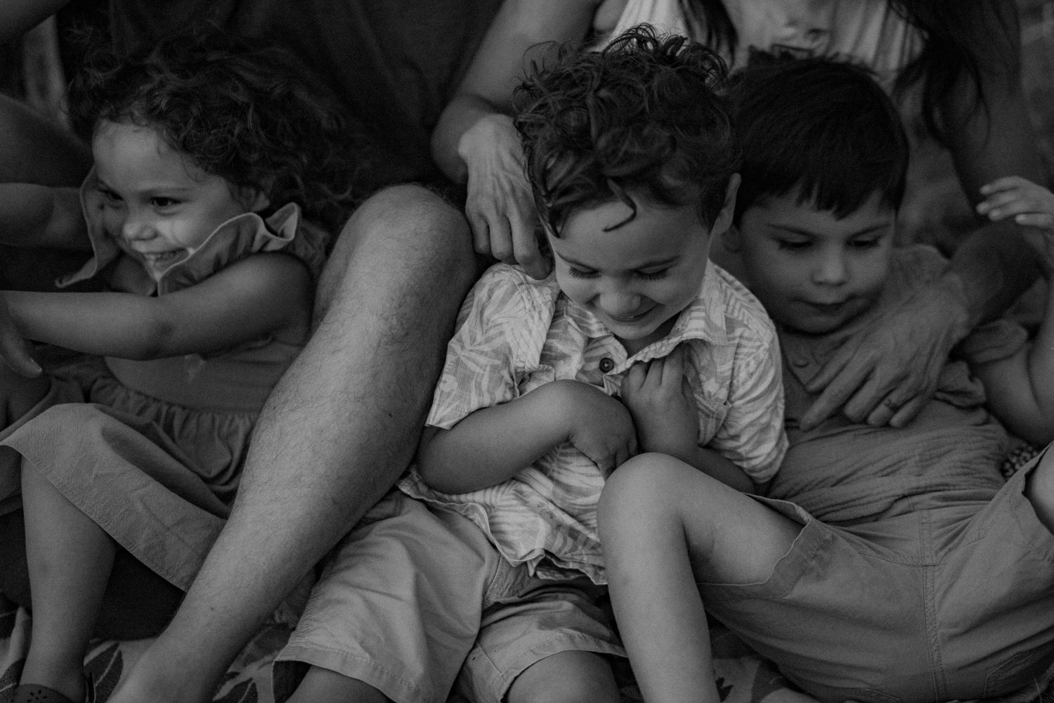 Vintage black and white photograph showing three children sitting together in casual summer clothing.