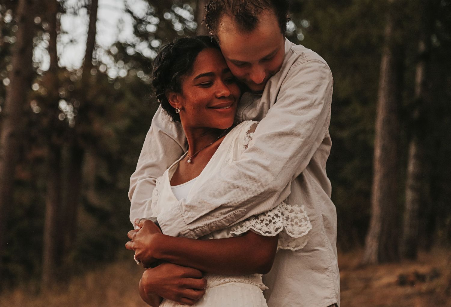 A couple shares an intimate embrace in a wooded outdoor setting during a romantic photo session.