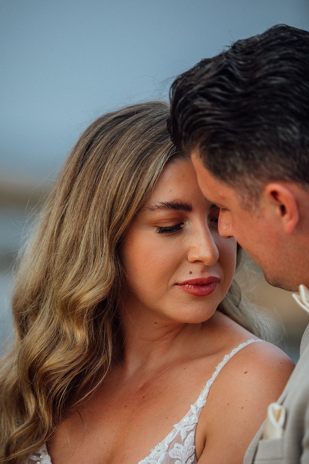 Romantic close-up of couple sharing an intimate moment on a shooting in Mallorca with bride wearing white lace dress and delicate makeup.