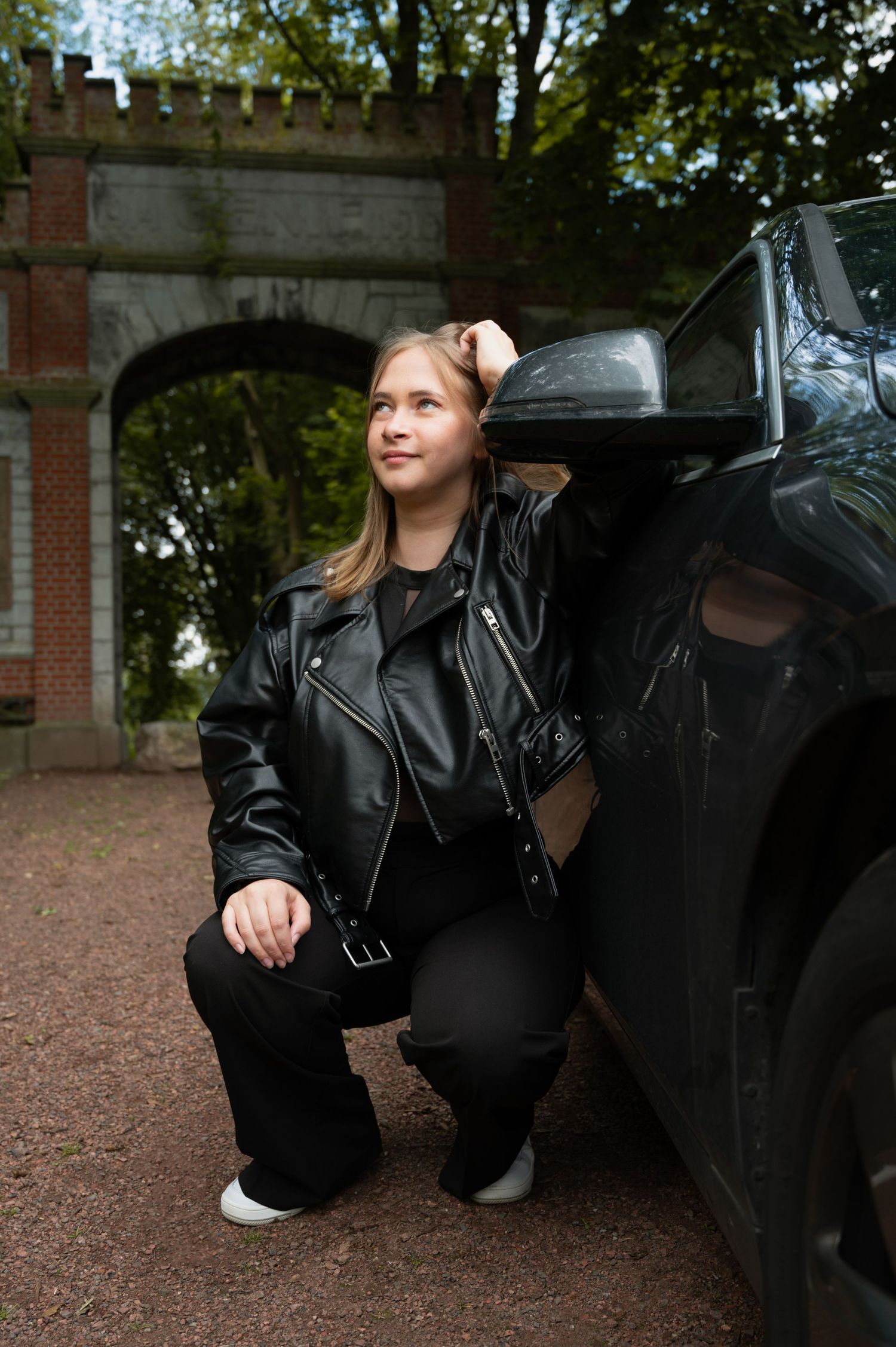 À Liège, au parc de la Chartreuse, portrait d’une femme accoudée contre sa voiture lors d’une séance photo en extérieur