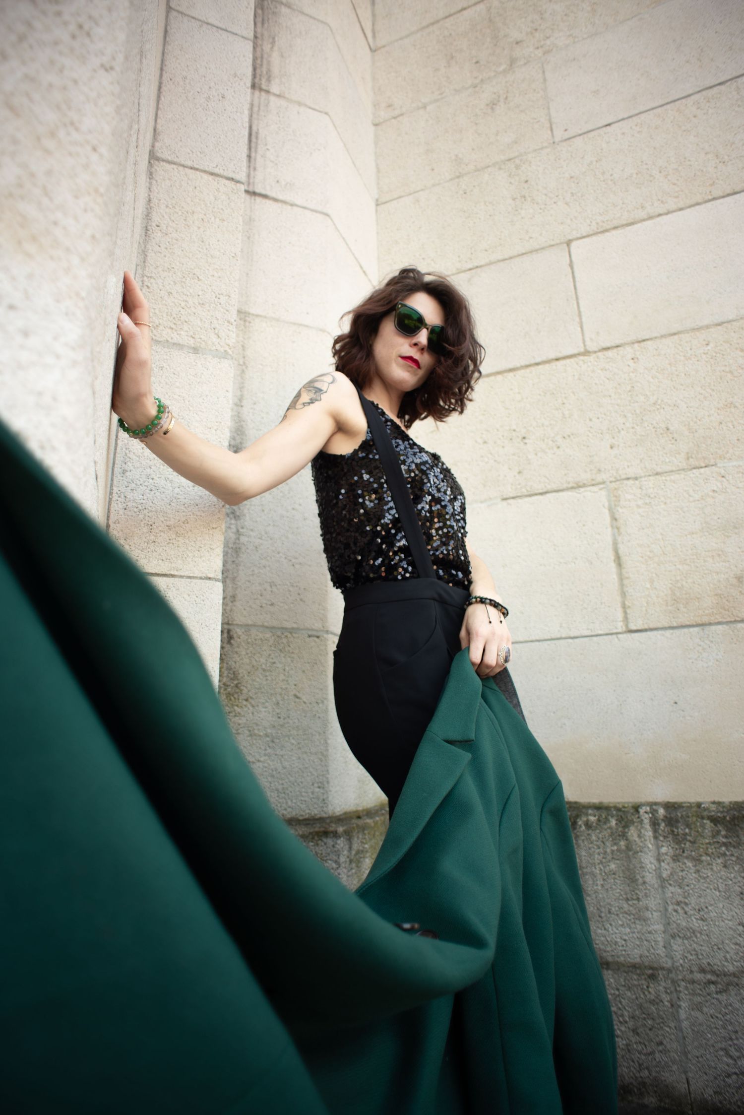 À Liège, au mémorial interallié de Cointe, portrait d’une femme tenant sa veste et portant des lunettes de soleil lors d’une séance photo en