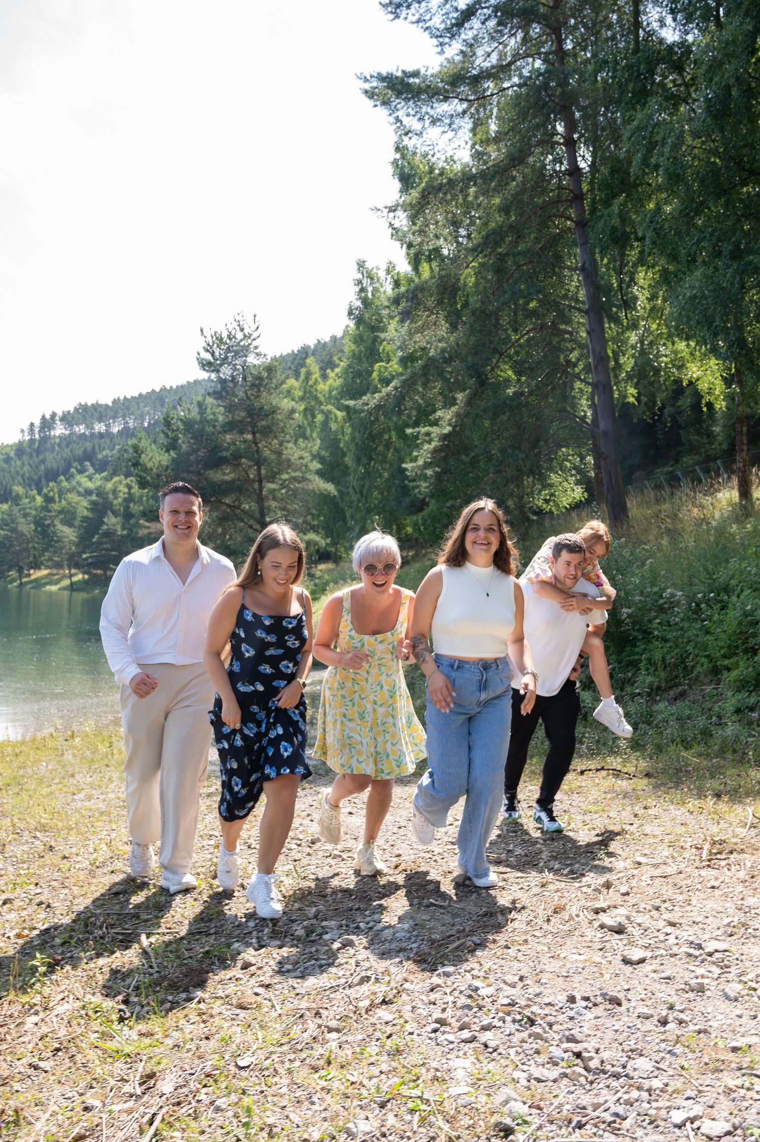 Groupe d’amis qui courent au bord du lac de Coo lors d’une séance photo amusante