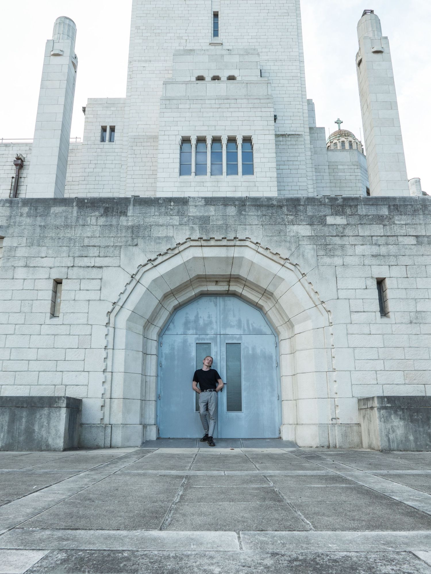 À Liège, au mémorial interallié de Cointe, portrait d’un homme posé contre la porte du monument lors d’une séance photo urbaine