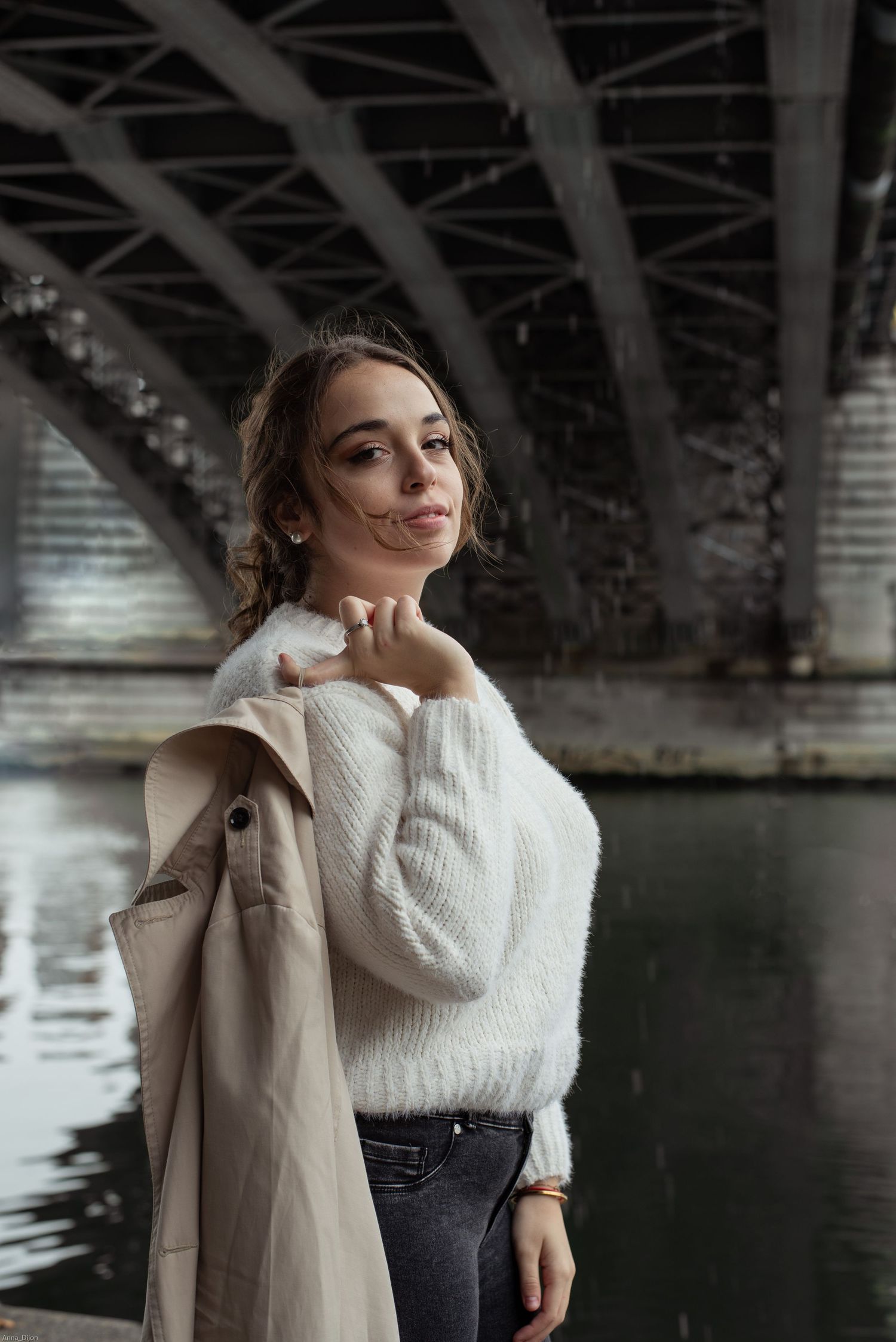 À Liège, sous le pont de Fragnée, portrait en extérieur d’une femme tenant sa veste sur le côté et regardant la caméra lors d’une séance pho