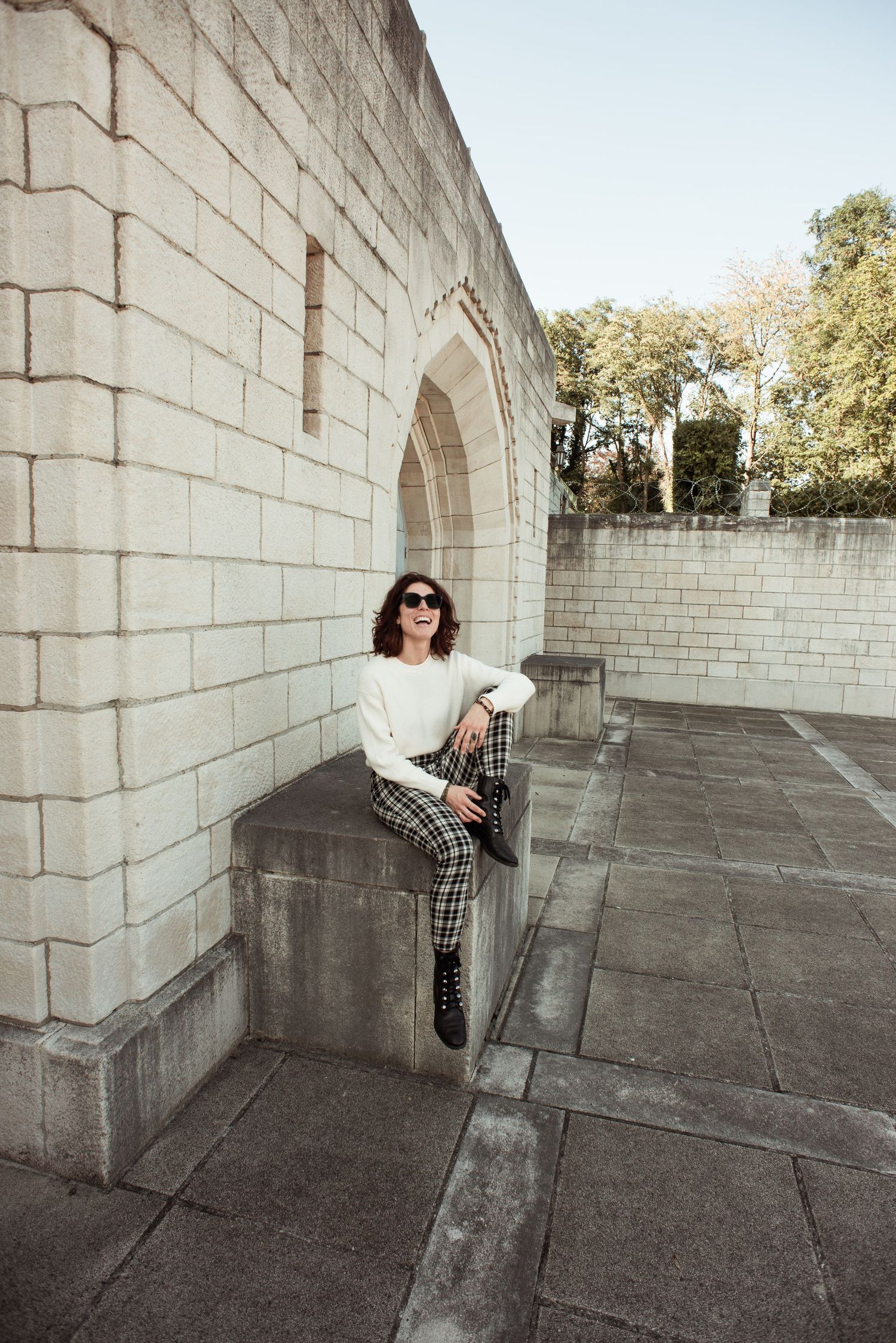 Femme devant le mémorial interallié de Liège assise  et souriante lors d’une séance photo