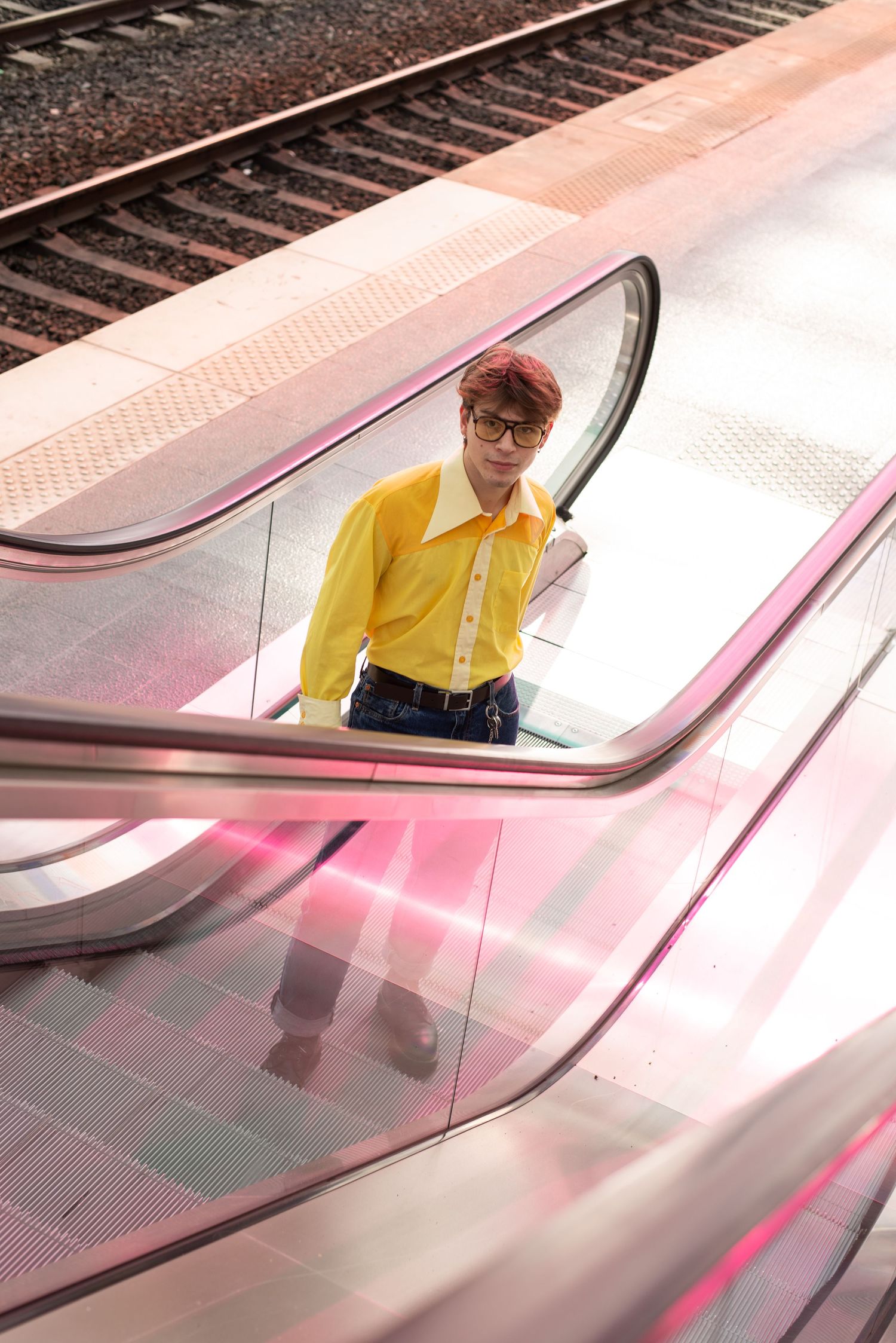 À Liège, à la gare des Guillemins, portrait d’un homme dans les escalators colorés avec un reflet rose de l’œuvre de Daniel Buren