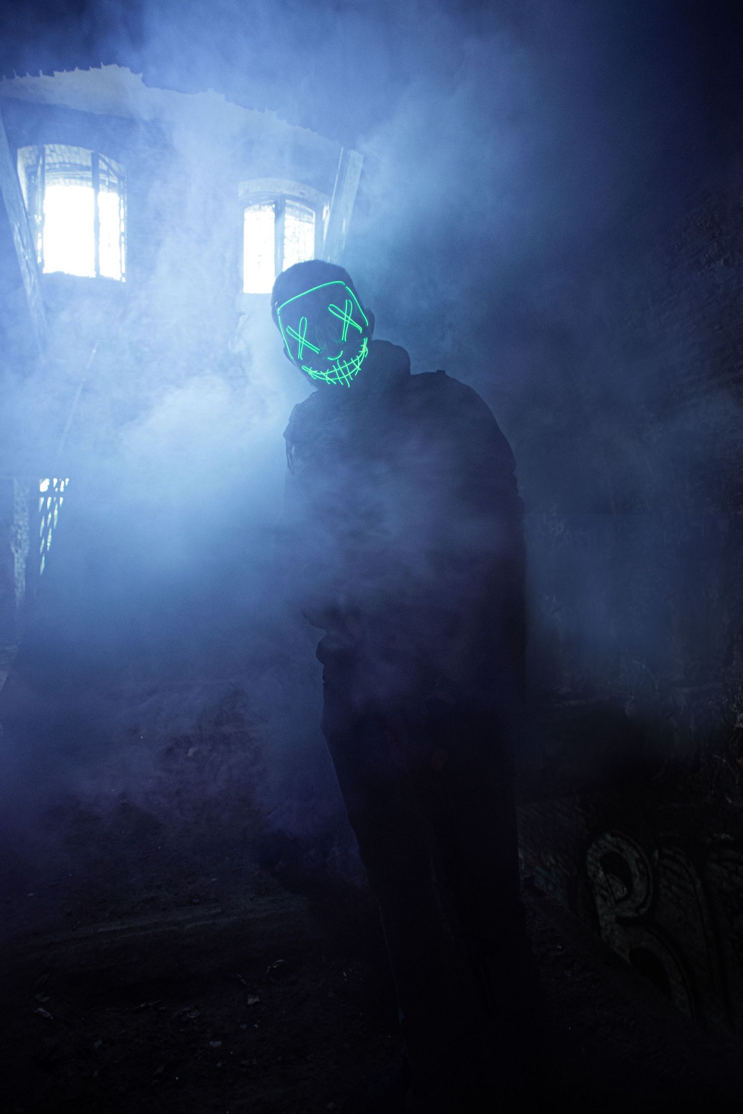 À Liège, au fort de la Chartreuse, portrait urbex d’un homme portant un masque lumineux et utilisant un fumigène lors d’une séance photo art