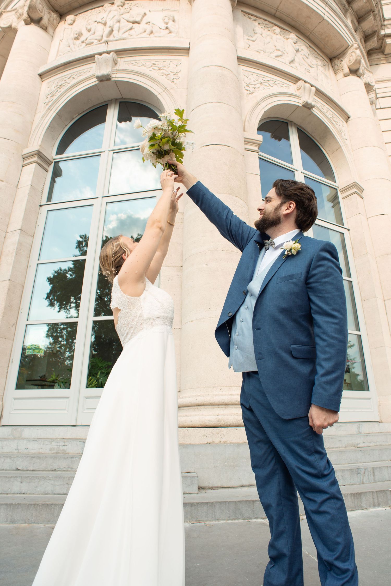 Séance photo de couple de mariés qui tiennent un bouquet de fleurs dans le parc de la Boverie à Liège