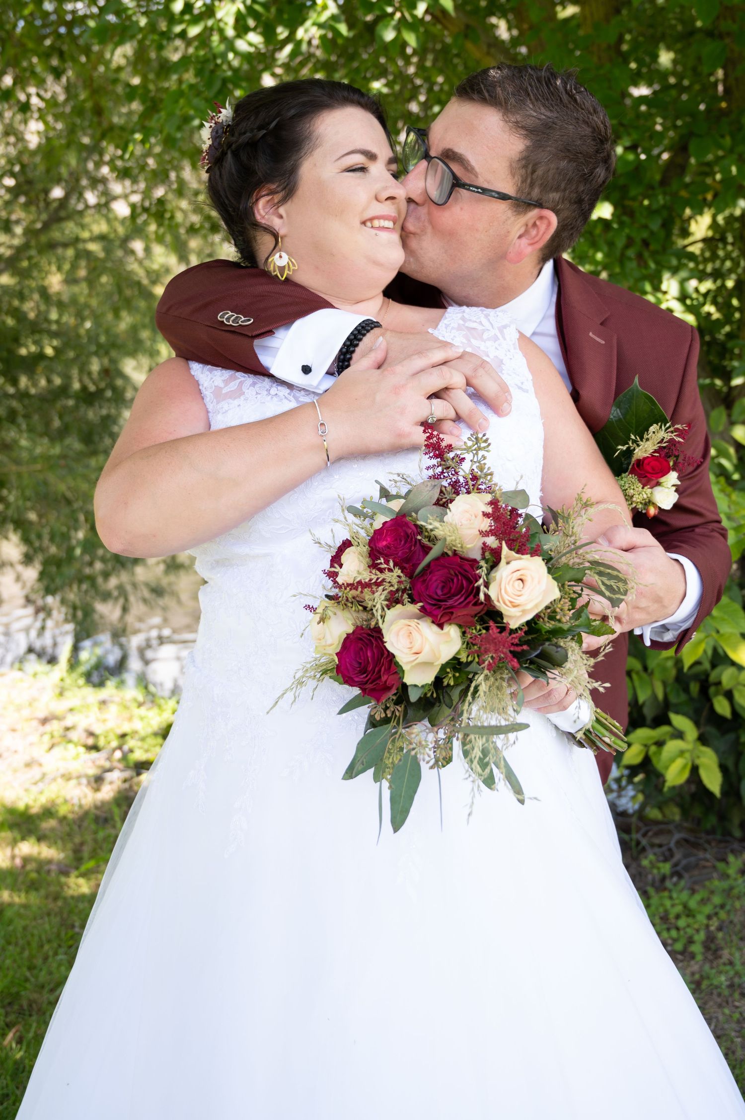 À Givet, séance photo de mariage d’un couple de mariés s’embrassant sous un arbre lors d’un moment naturel et romantique
