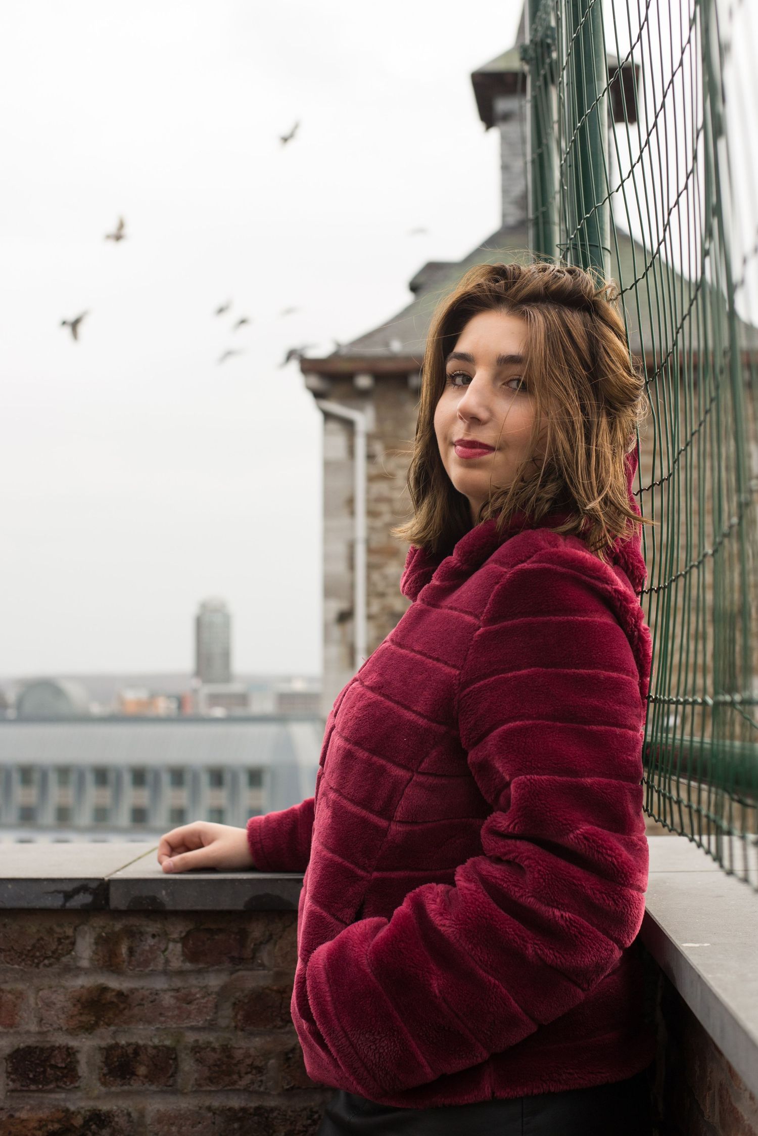 À Liège, à la Citadelle, portrait d’une femme photographiée avec une vue sur la ville en arrière-plan et des oiseaux en vol