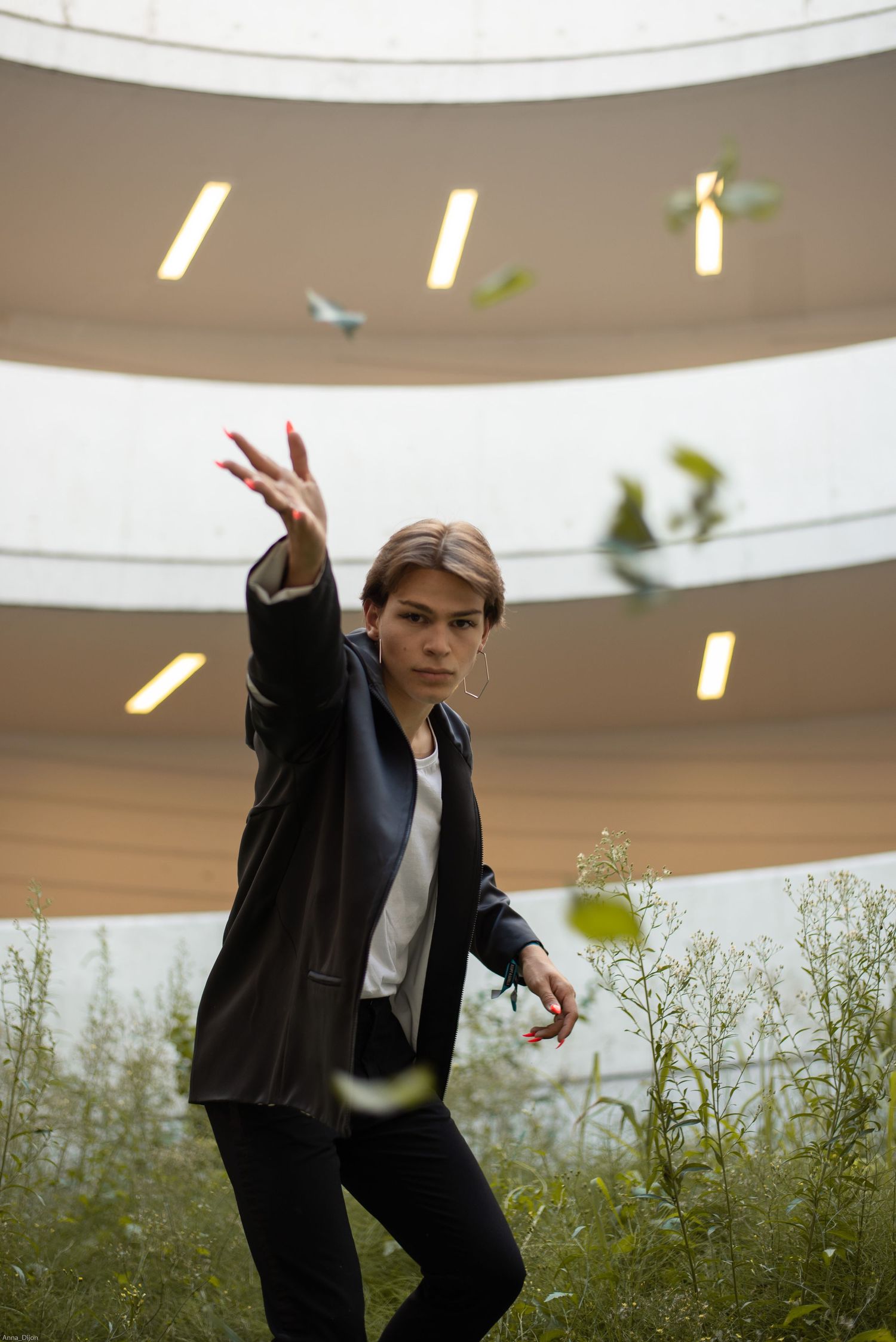 À Liège, dans le parking de la gare des Guillemins, portrait d’un homme lançant des feuilles vers l’objectif lors d’une séance photo urbaine
